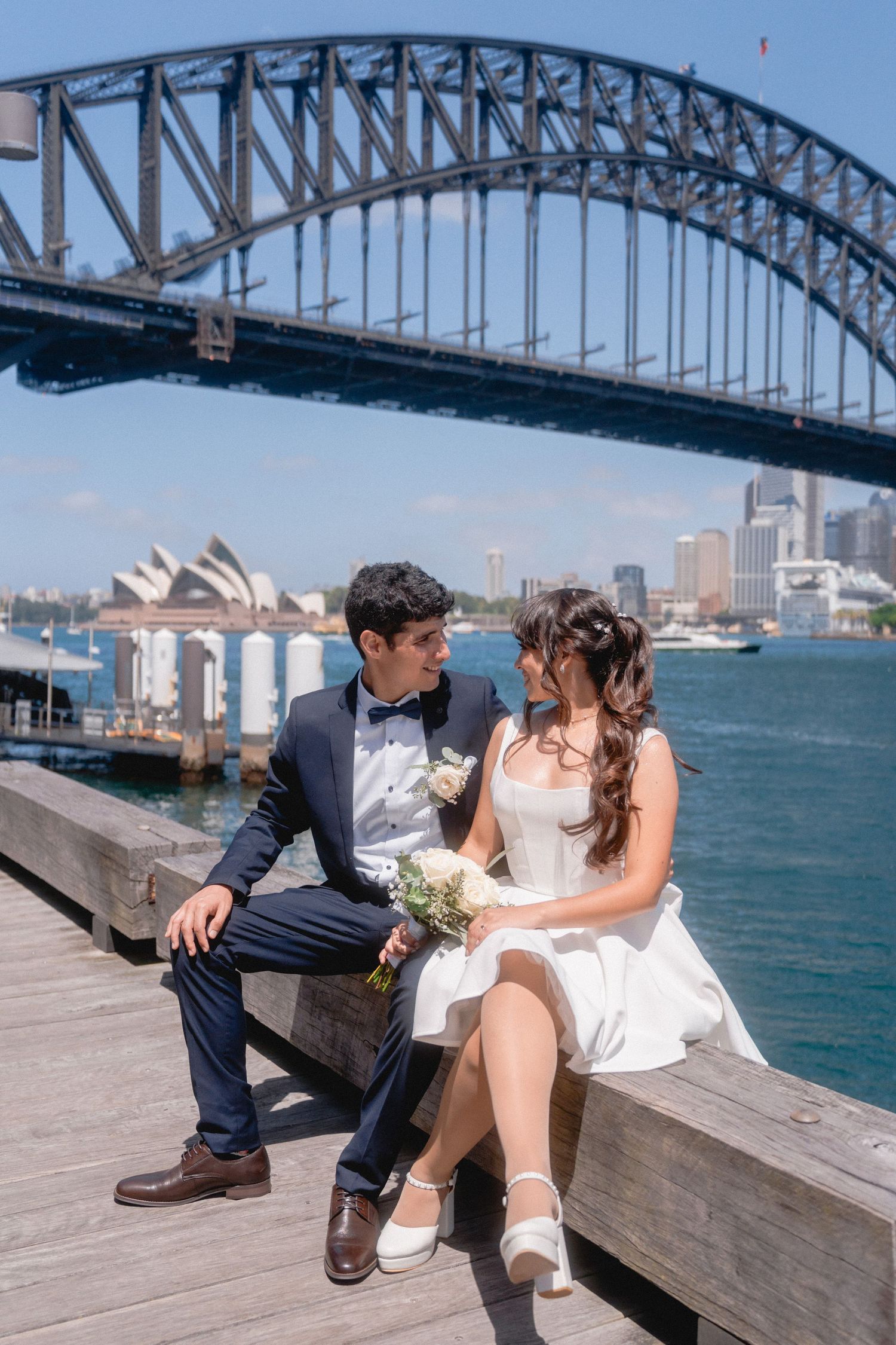 A romantic photoshoot by the Sydney Harbour Bridge with a couple on the boardwalk.