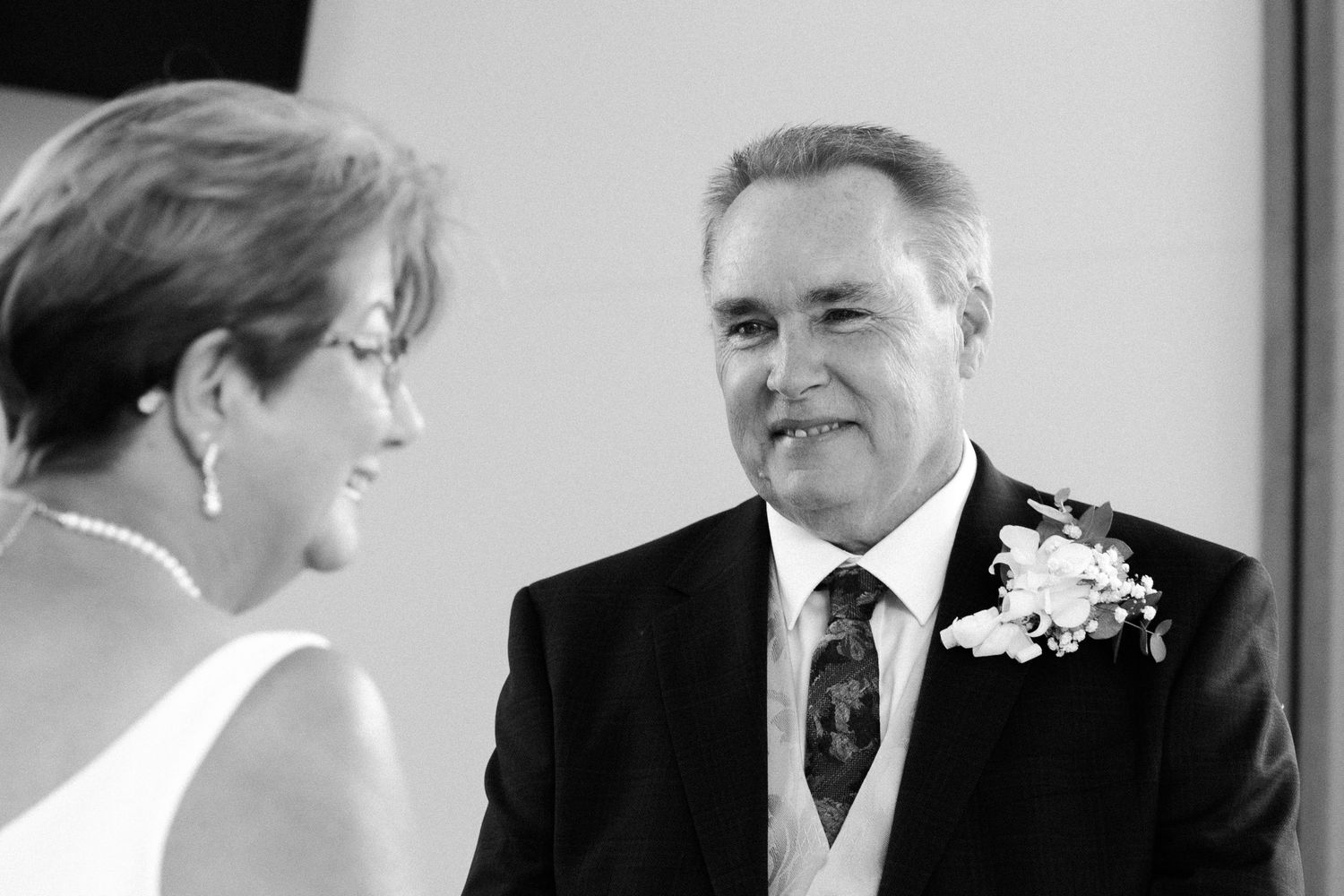 Black and white photo of a couple exchanging vows during their wedding ceremony.