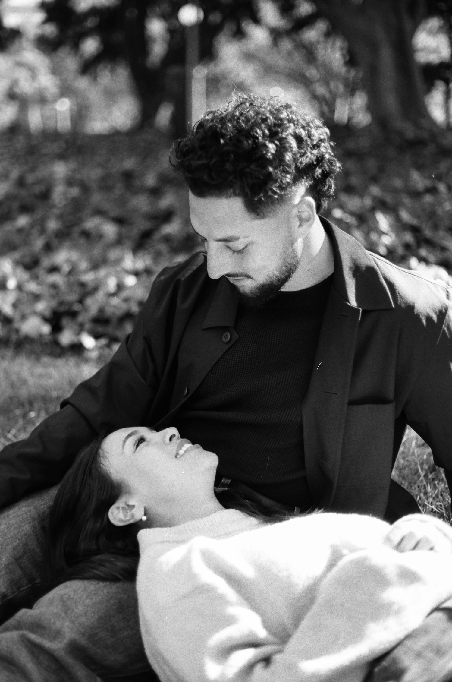A couple shares an intimate moment while relaxing in a park setting.