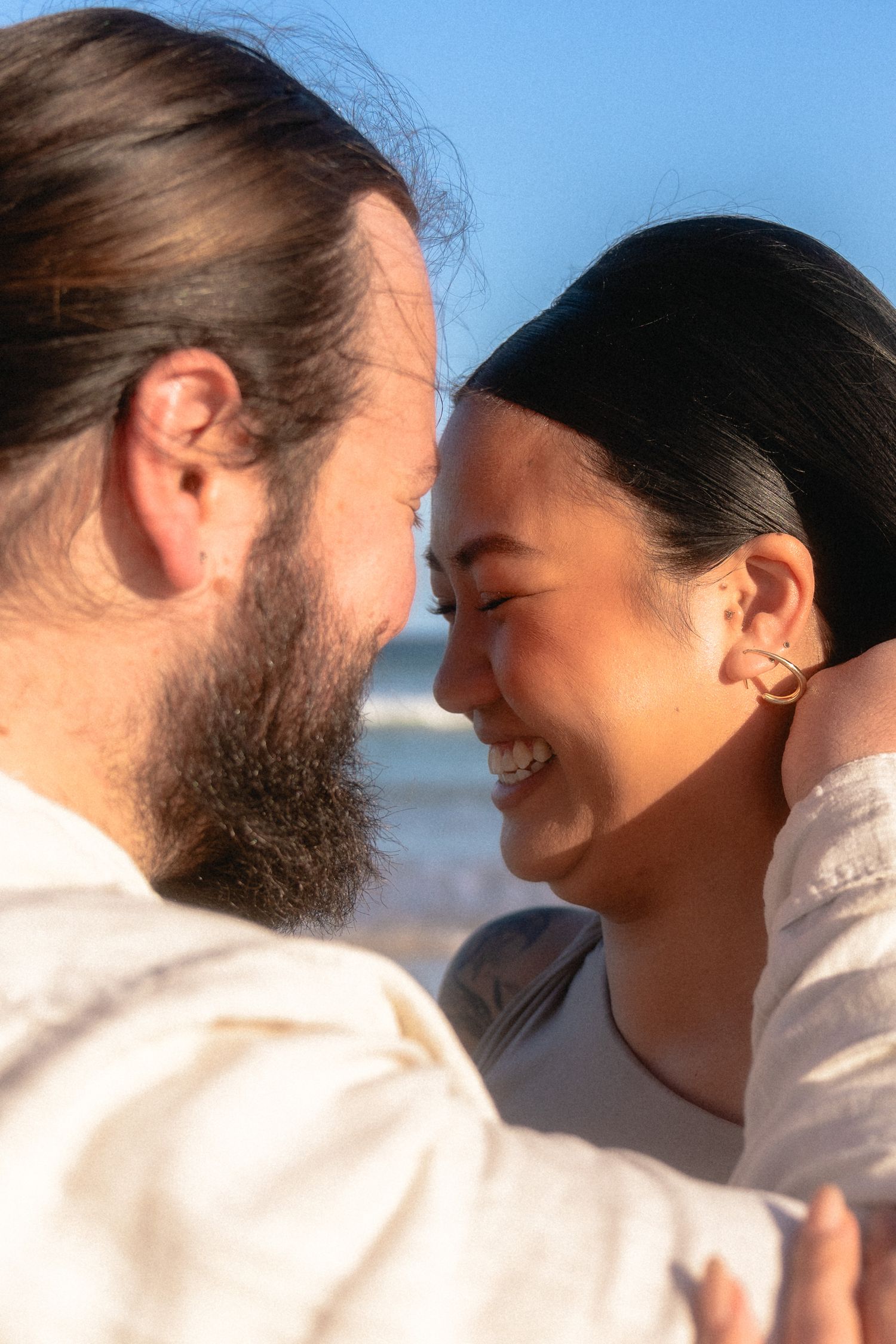 A couple shares an intimate moment against a bright blue sky background.