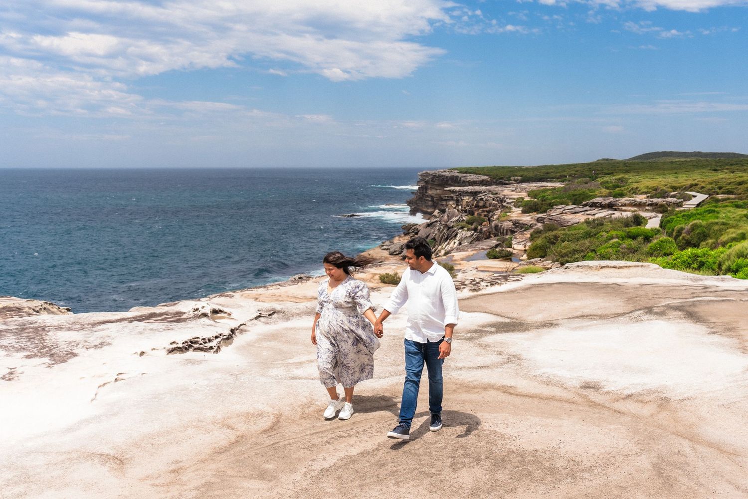 Scenic coastal landscape with rocky cliffs and ocean views under blue skies.