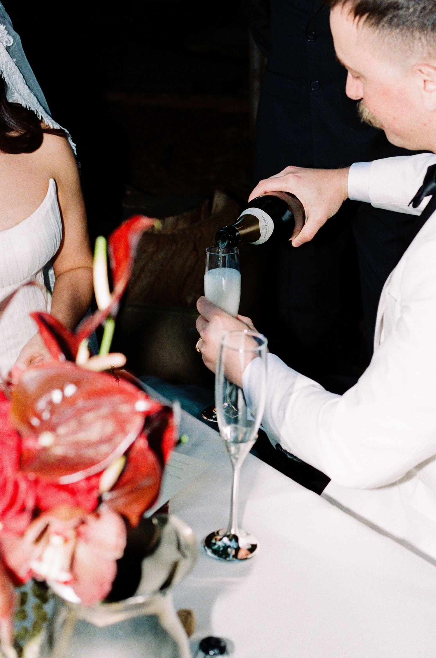 Wedding reception details showing white attire and red flower centerpieces.