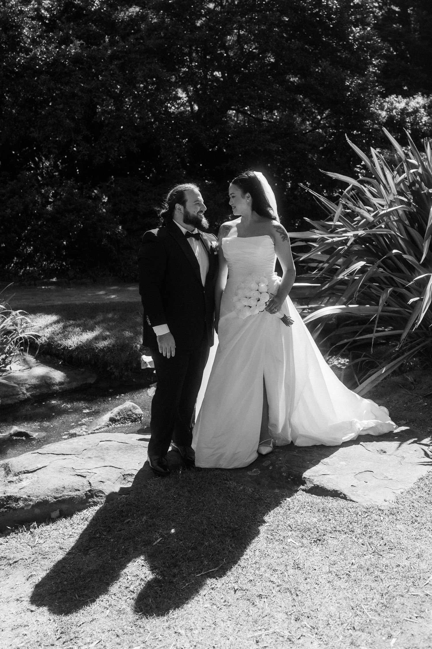 Black and white photos of a couple sitting outdoors casting long shadows on a gravel path.