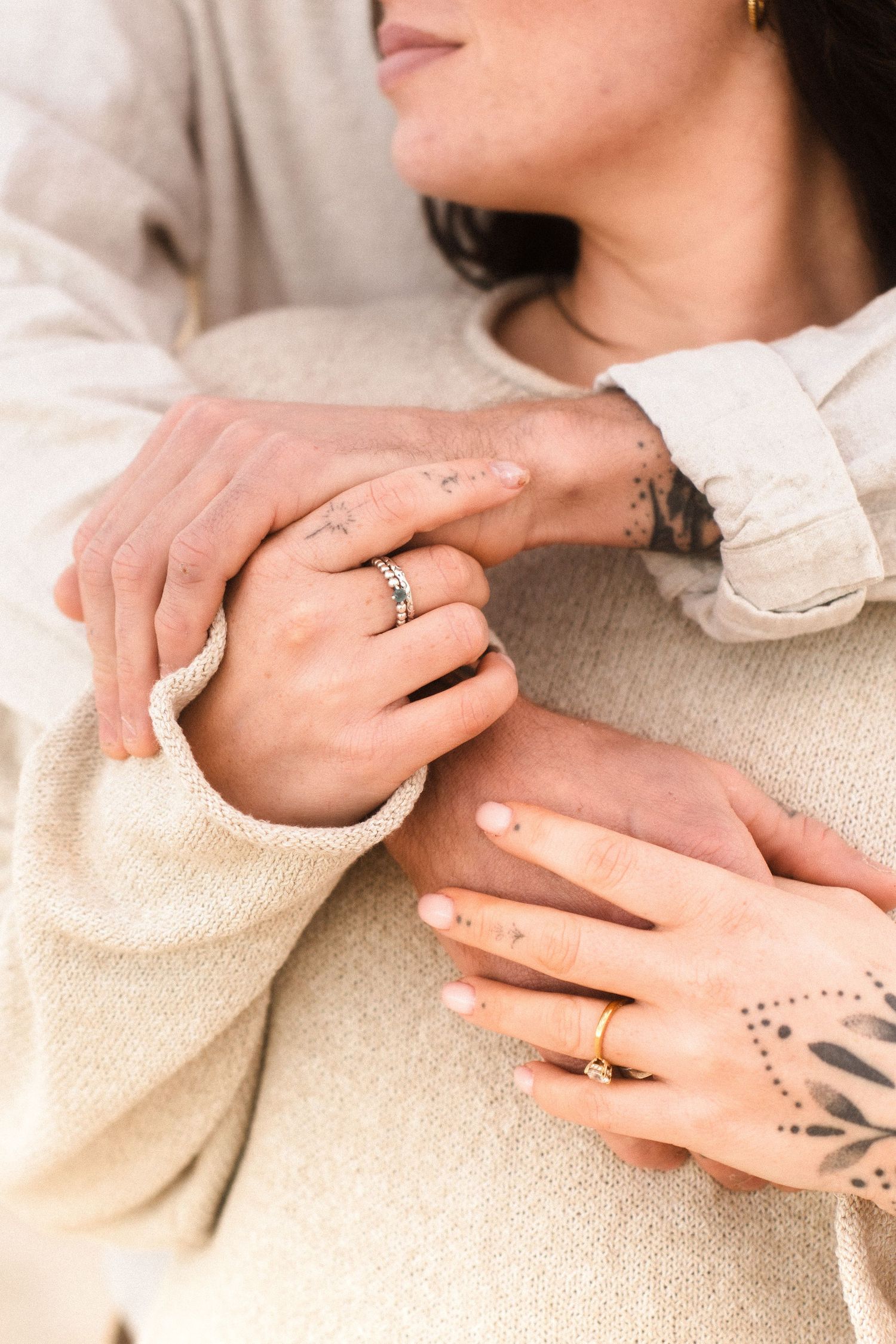 Detail shot of hands with henna tattoo and engagement ring in warm light.