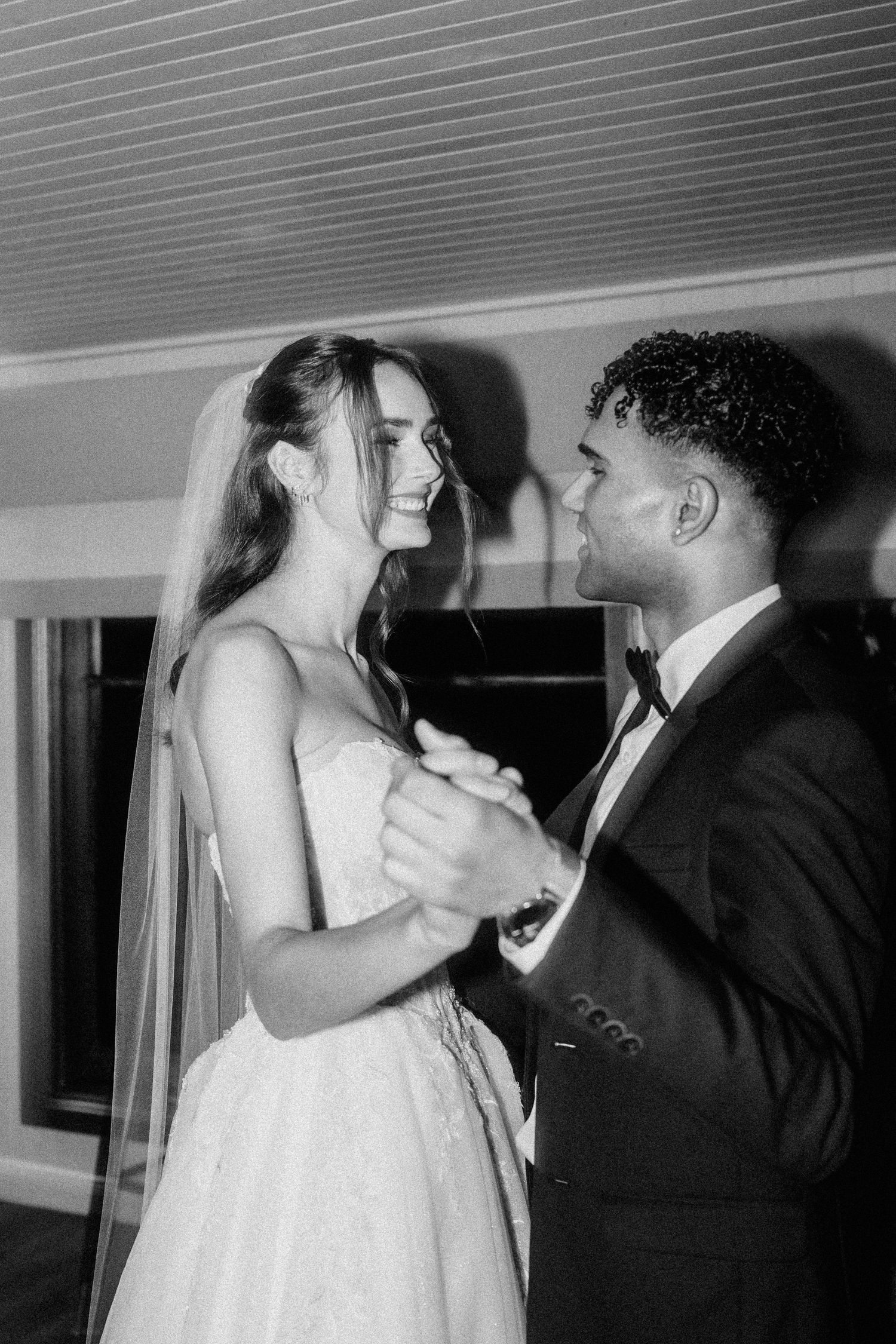 A tender moment between newlyweds dancing in a rustic indoor setting.