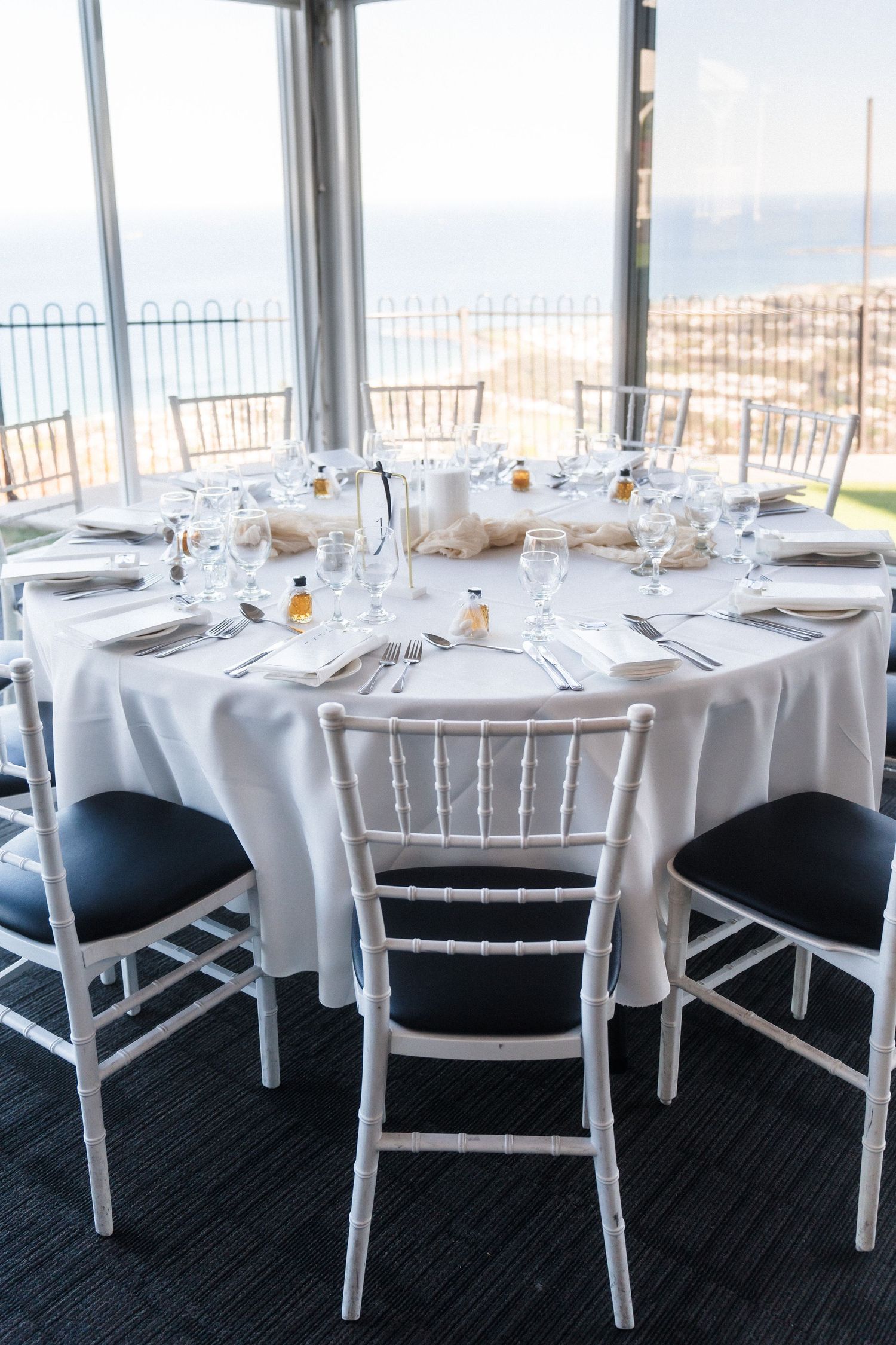 Elegant wedding reception tables with white linens and chiavari chairs overlooking mountain views.
