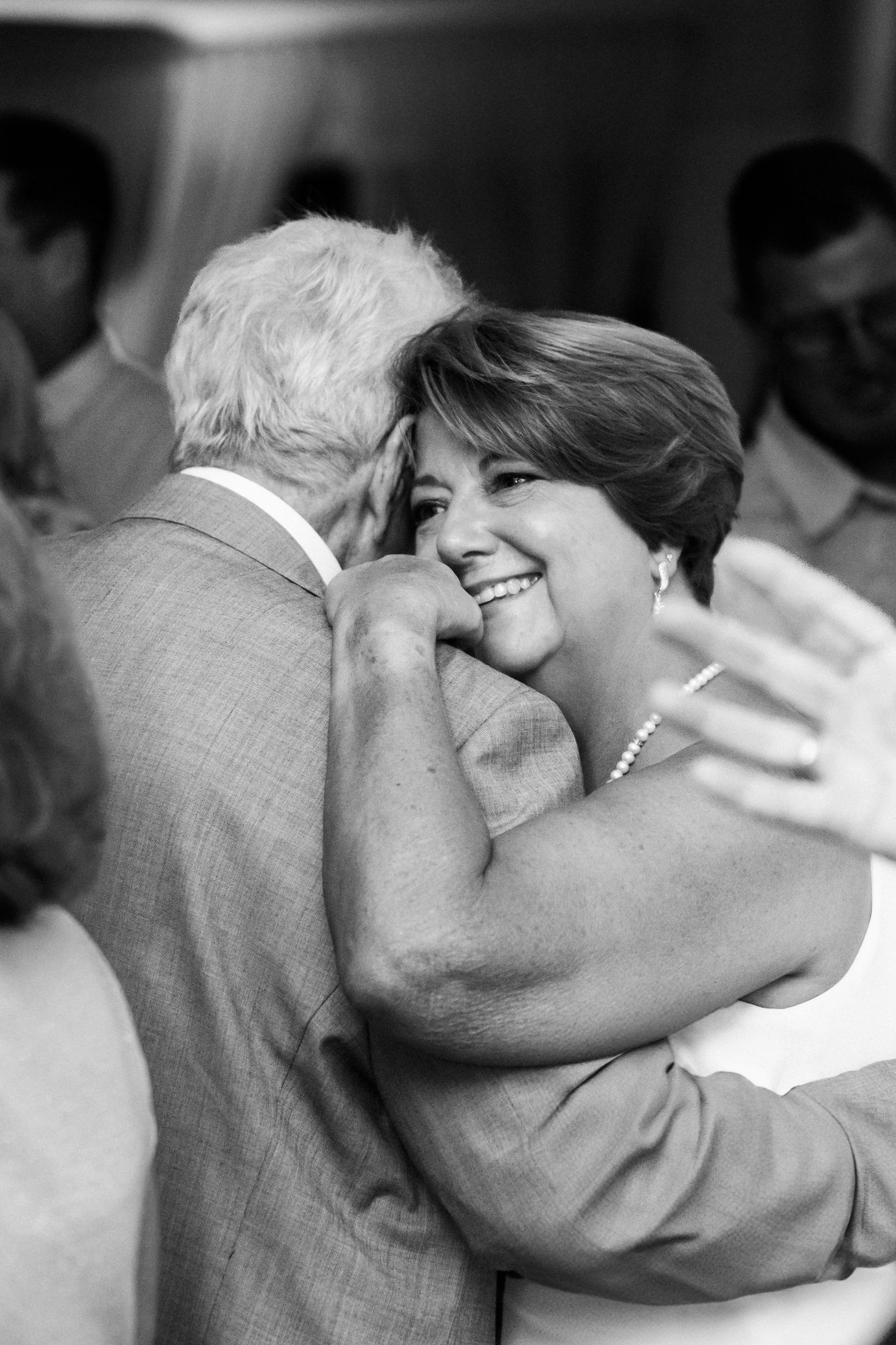 A tender moment captured in black and white as two people share a joyful embrace during a celebration.