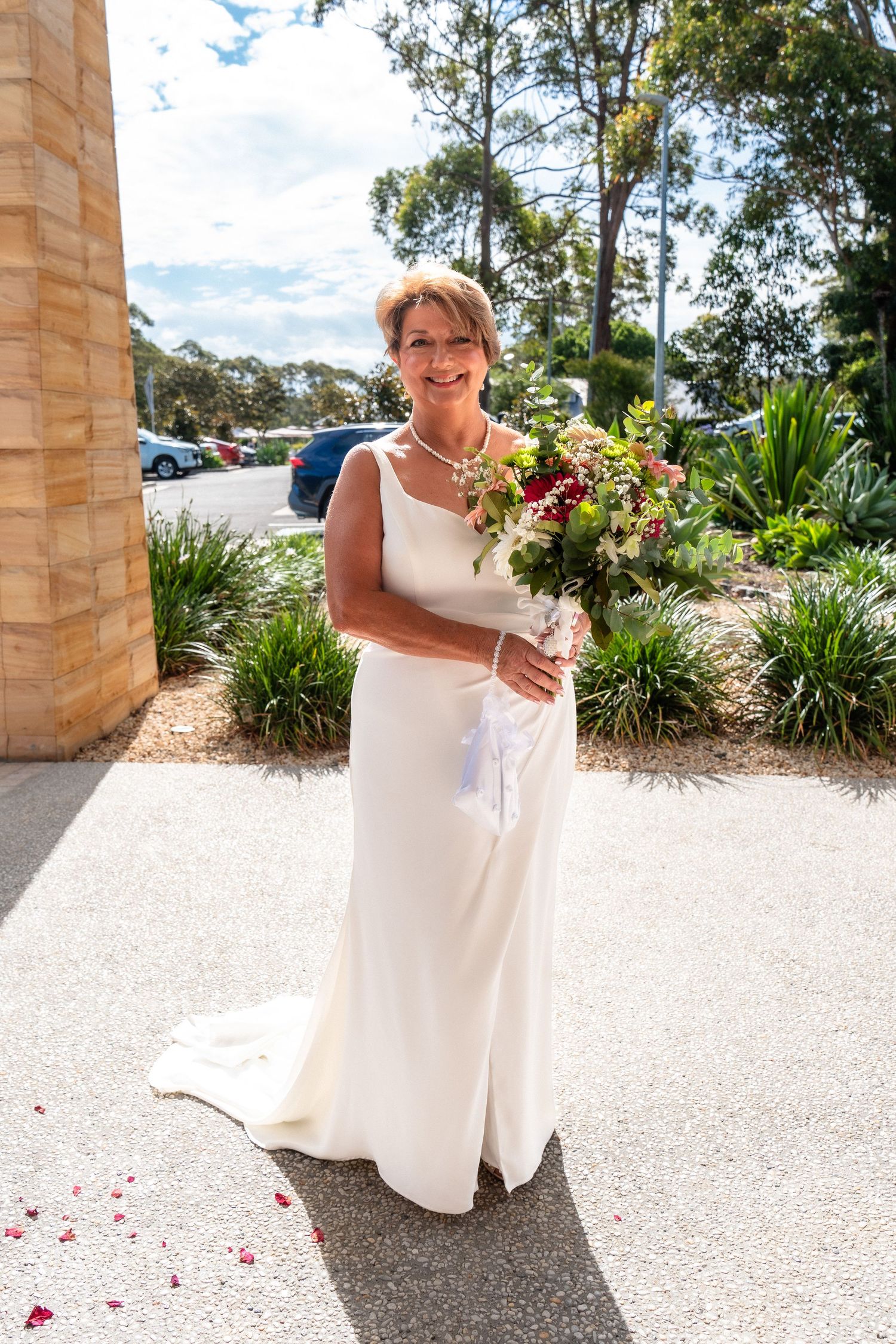 Person in white dress walking on stone path with scattered rose petals.
