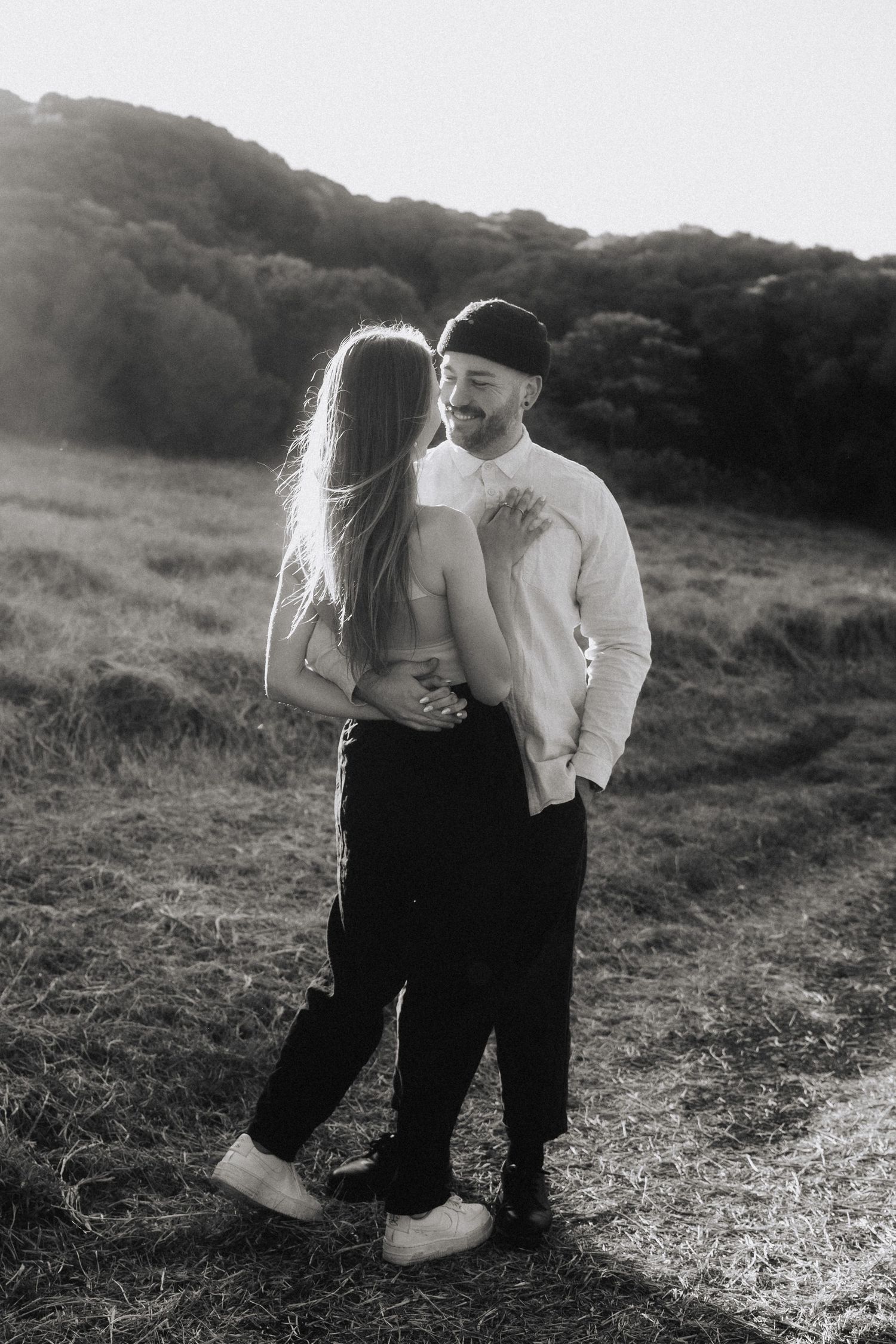 Black and white photos of a couple sharing tender moments on a hillside.