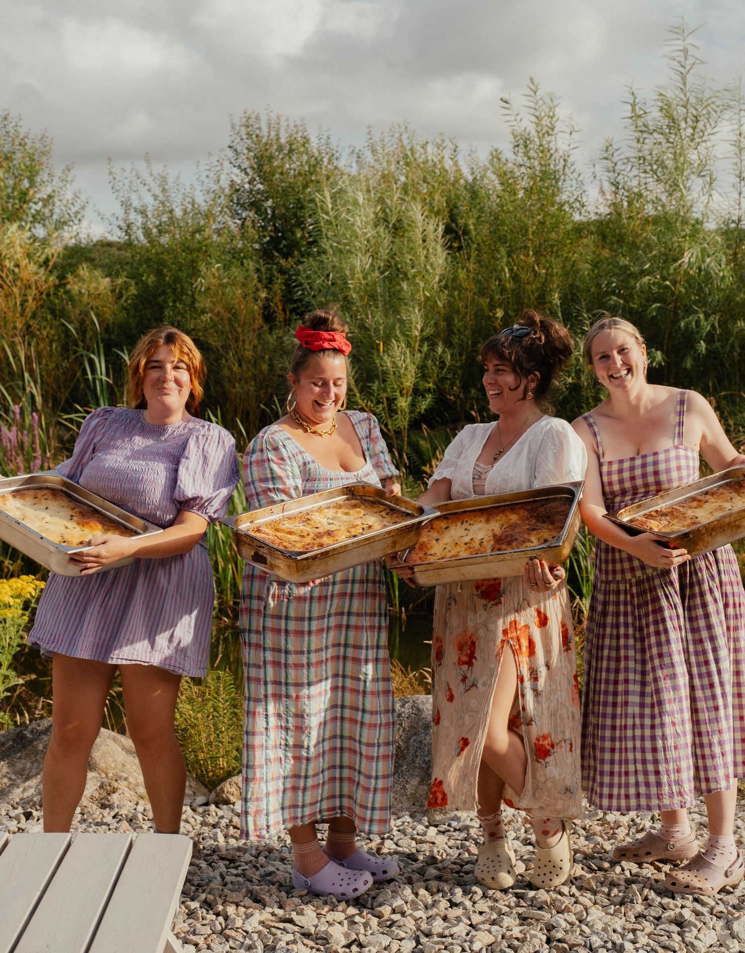 People holding wooden serving boards outdoors in casual summer attire.