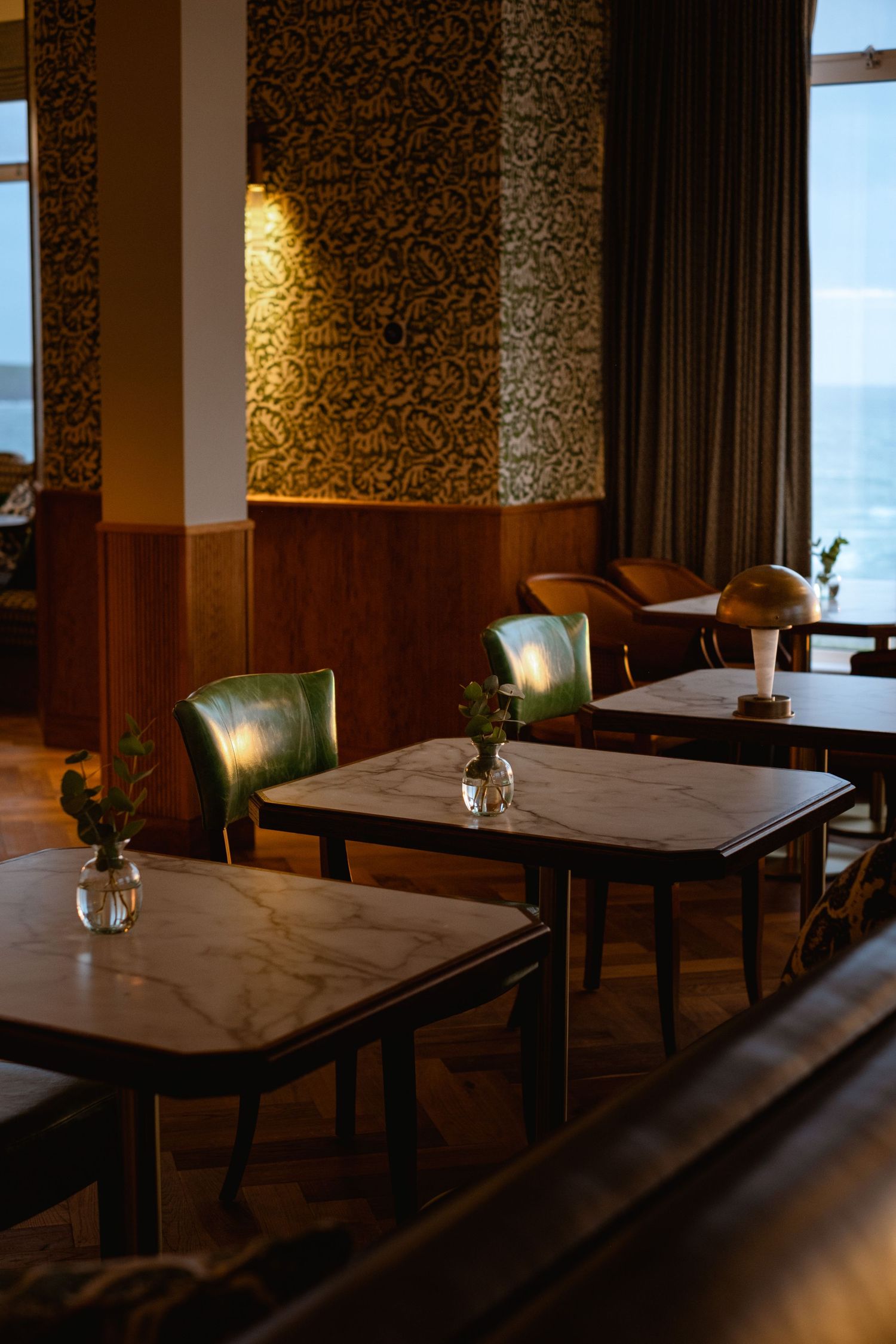 Dimly lit restaurant interior with elegant tables set against patterned wallpaper and soft lighting creating an intimate ambiance.