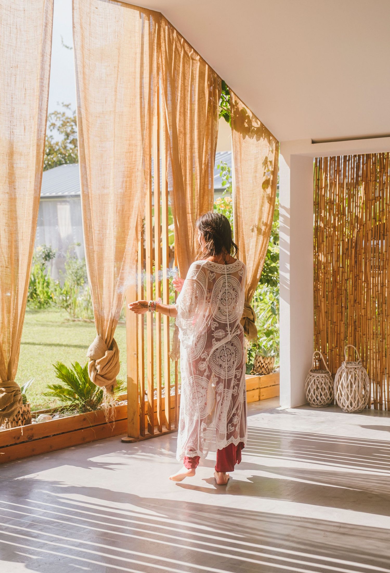 Sun-drenched porch with bamboo curtains creating striped shadows on wooden flooring.