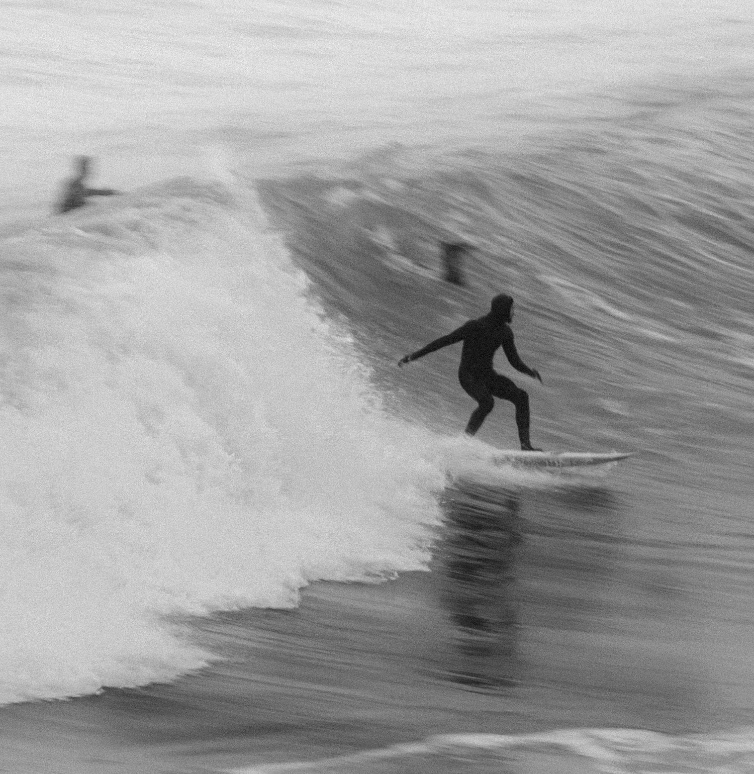 Black and white sequence of a surfer riding ocean waves from left to right.