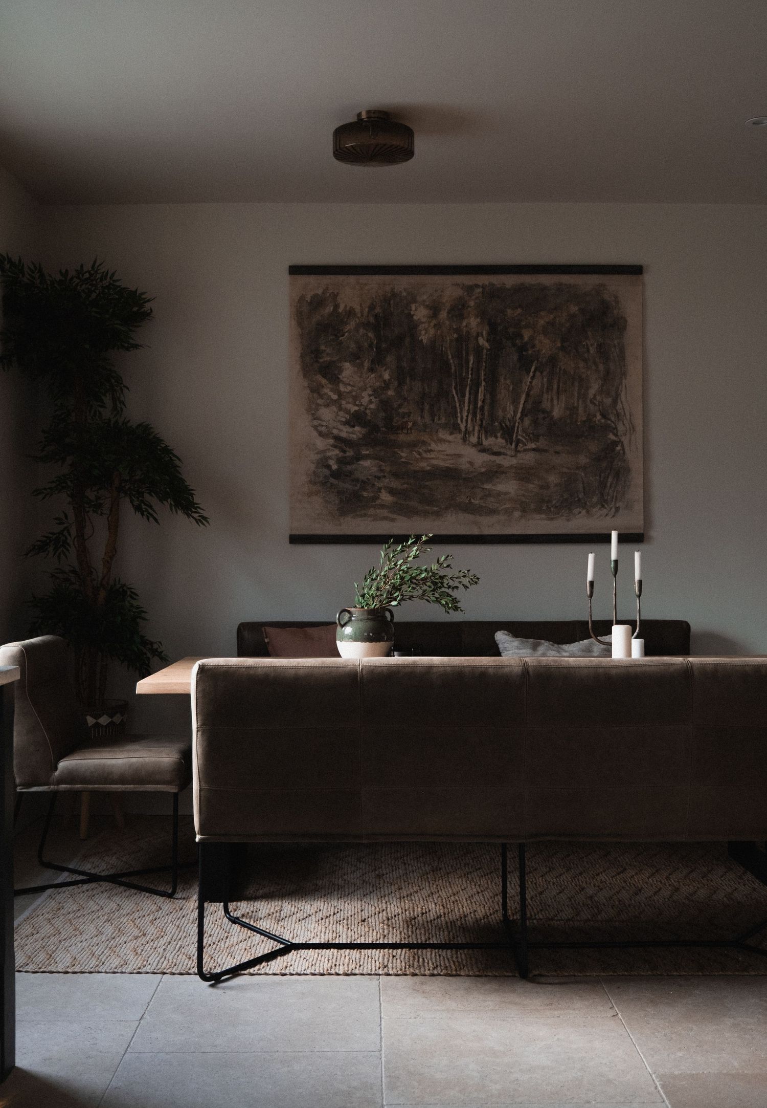 Modern minimalist living room with dark furniture and artistic wall hangings in natural light.