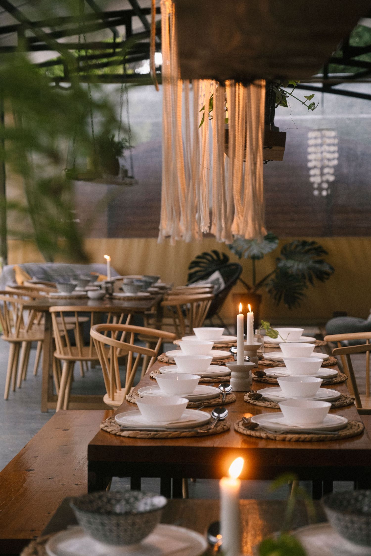 Elegant restaurant interior with wooden tables set with white plates and candlelight creating a warm ambiance.