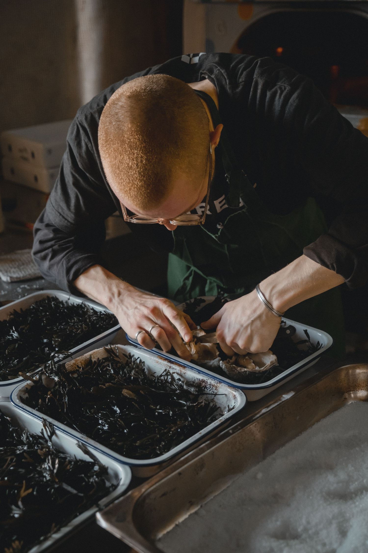 Close-up of hands working with dark soil or compost in metal trays.