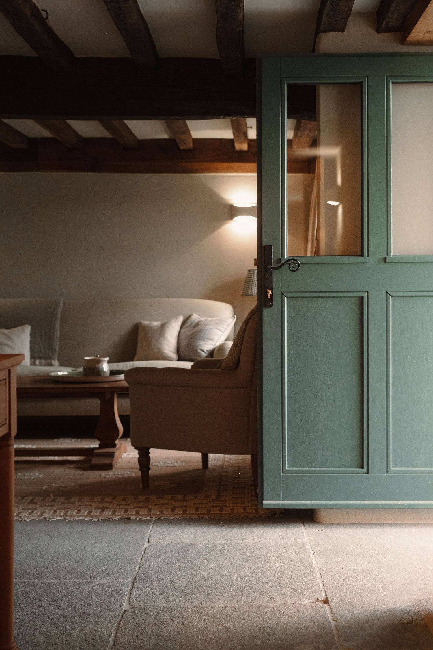 Rustic interior with exposed wooden beams and sage green cabinet doors against a neutral wall.