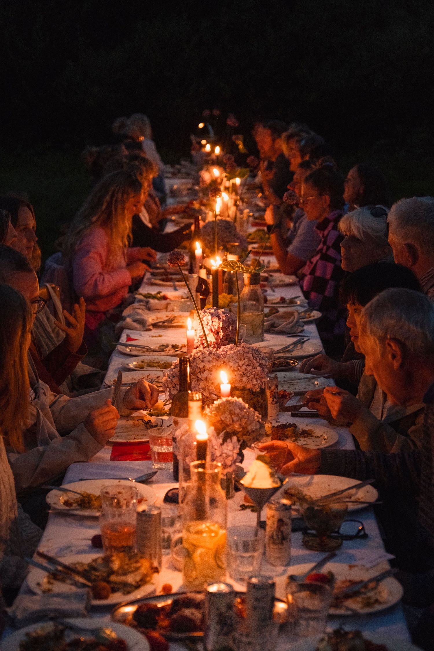 Long dining table set with candles for evening outdoor dinner party.