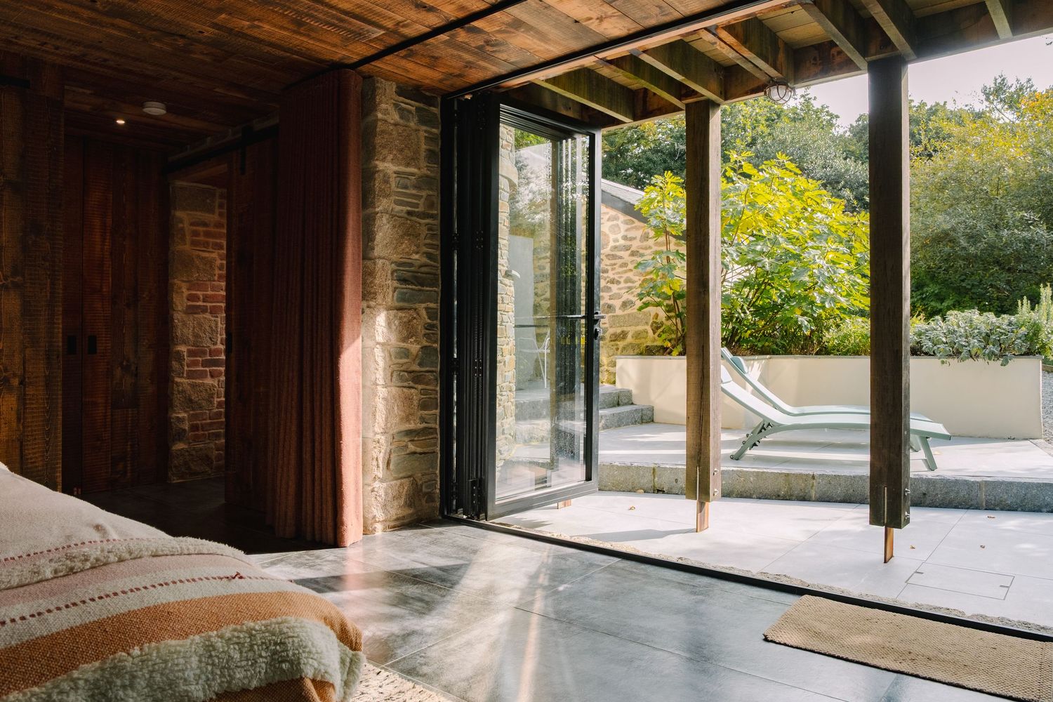 Modern glass-walled room with wooden beams and natural light streaming in.