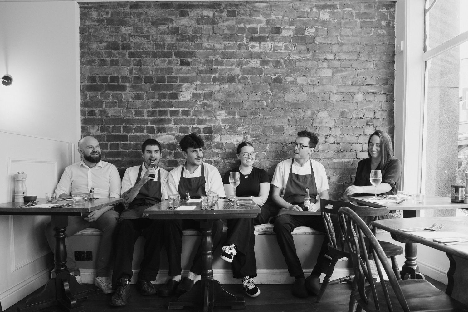 Long dining table against exposed brick wall with people seated.