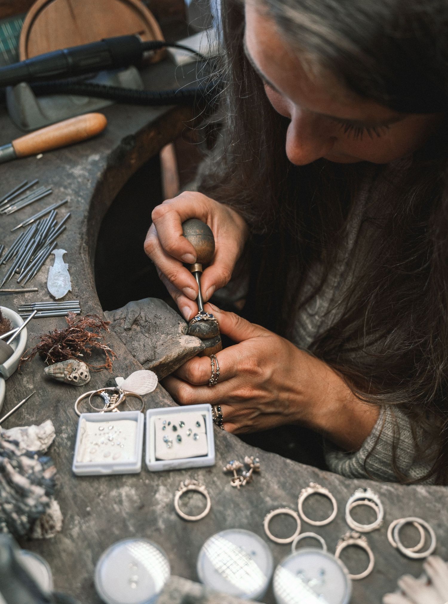 Artisan crafting jewelry or small metalwork pieces at a workbench.