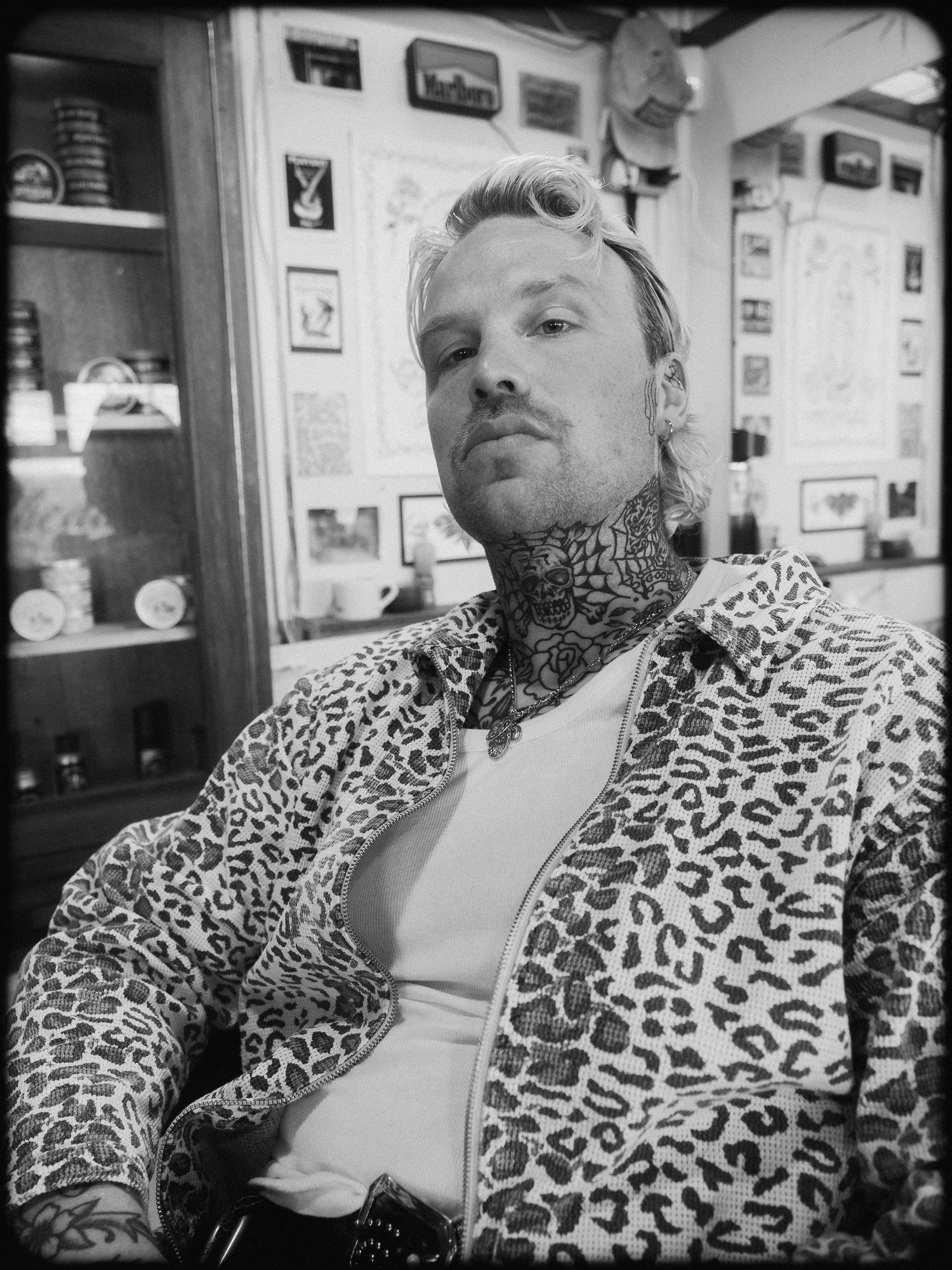 A series of black and white photos showing someone in a leopard print jacket sitting in what appears to be a cafe setting.