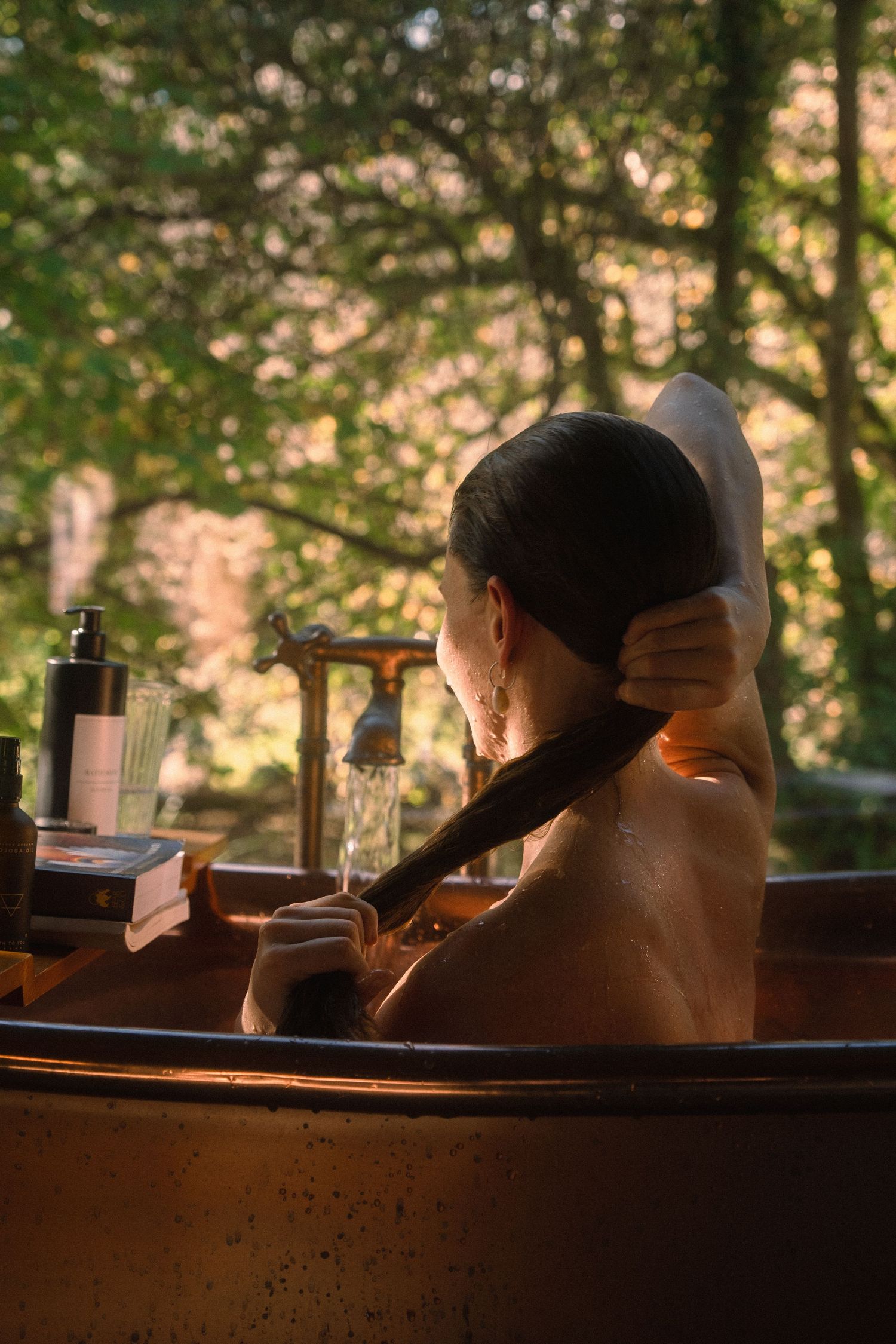 Relaxing outdoor bath scene at sunset with bath products and natural surroundings.
