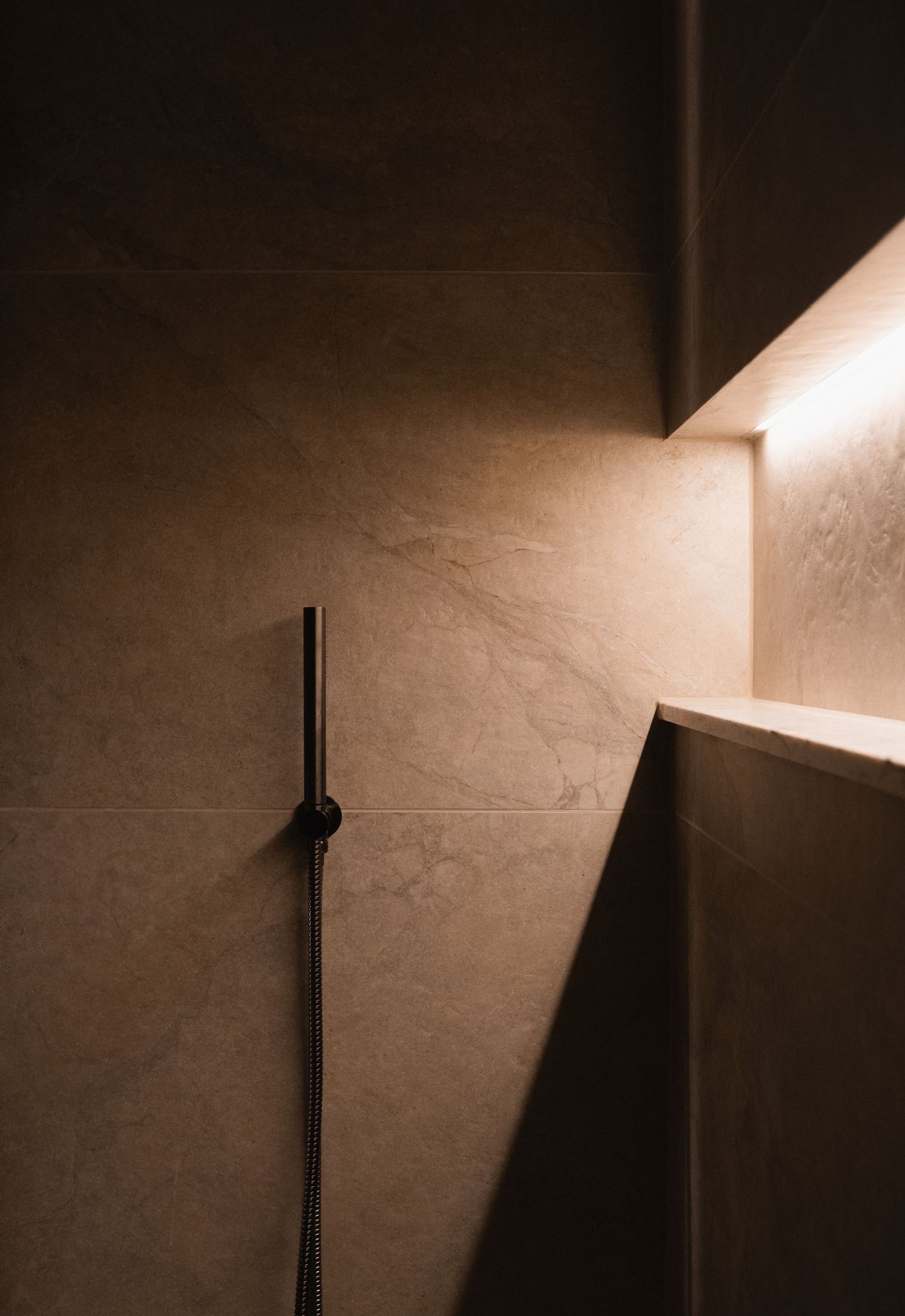 Dramatic shadows cast on textured wall with minimalist black pole installation.