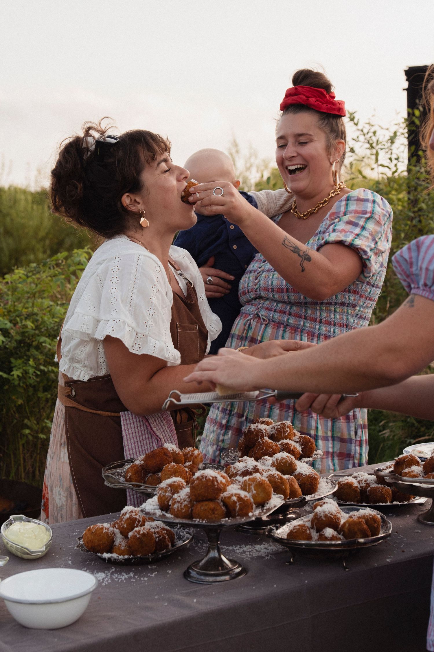 Group enjoying powdered pastries and desserts at an outdoor gathering.