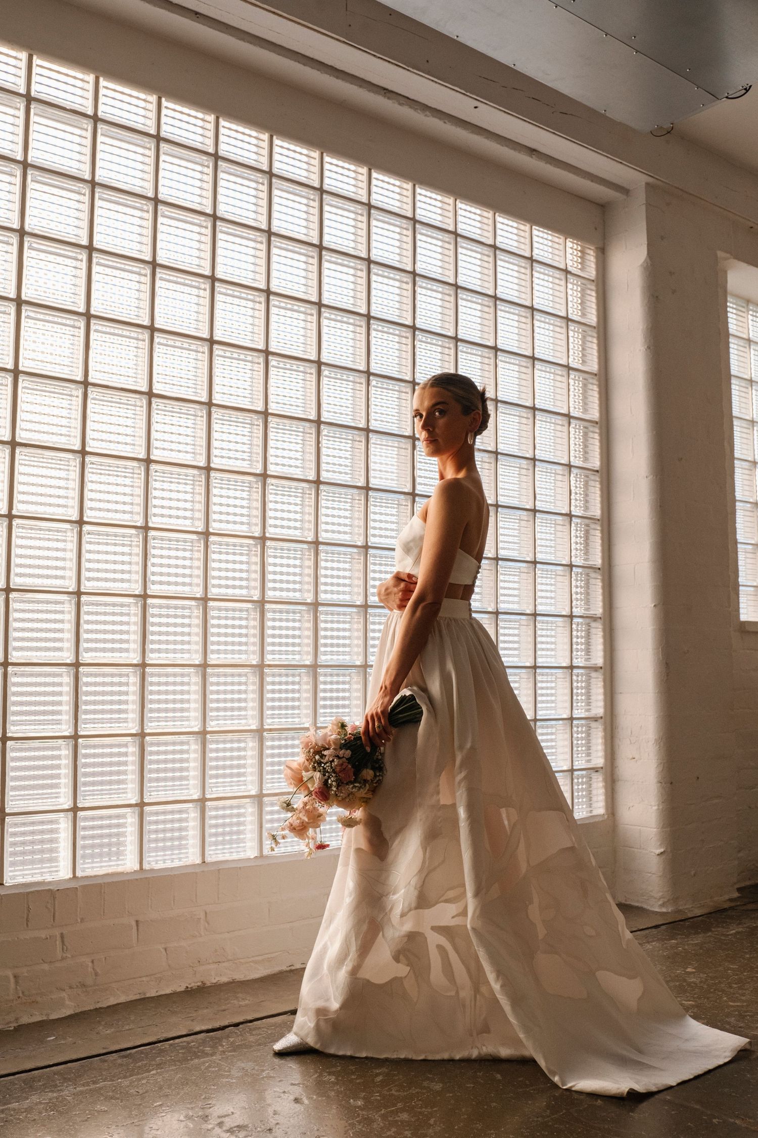 Sunlit studio space with white brick walls and large industrial windows creating dramatic lighting.