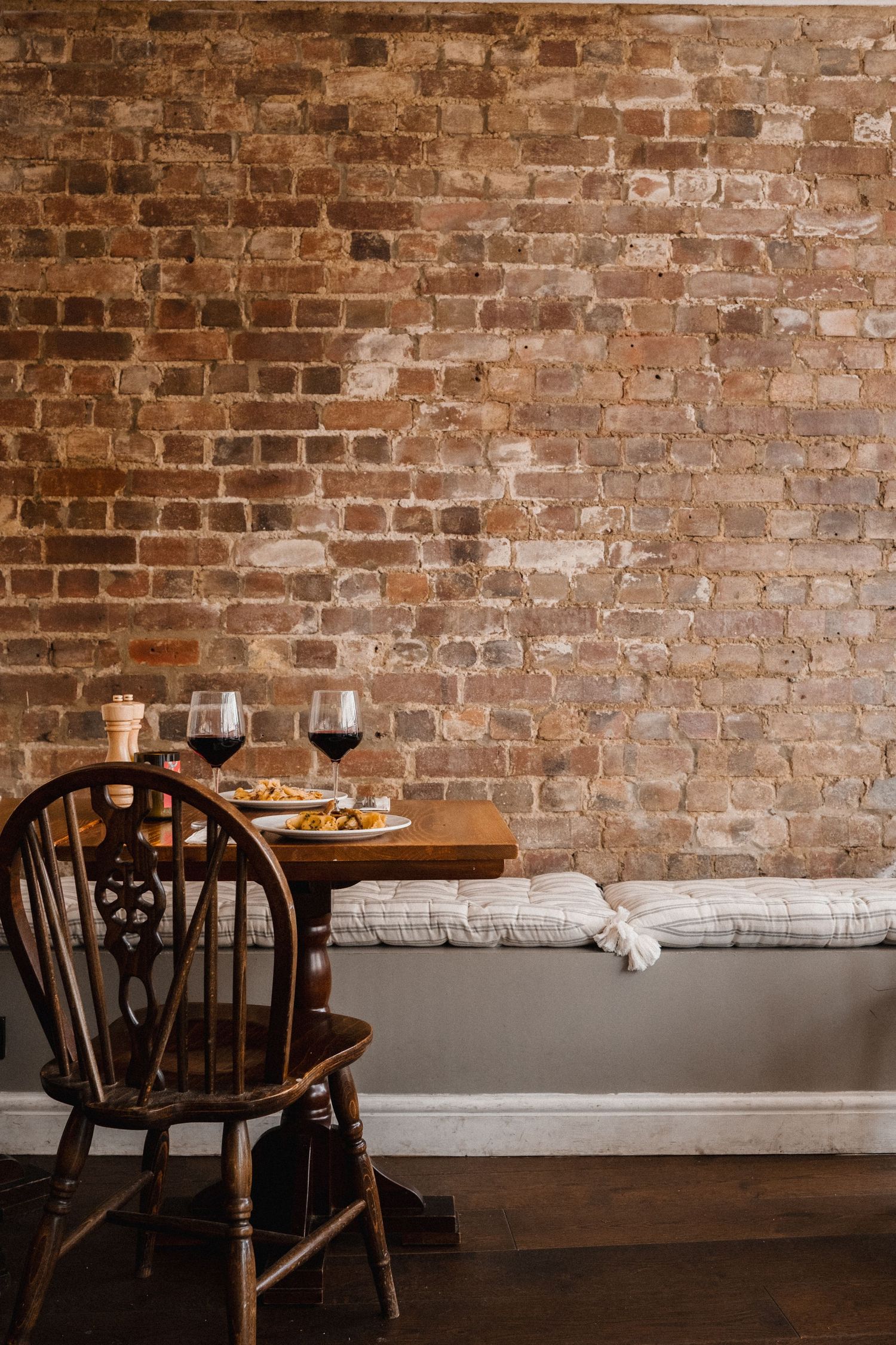 Rustic dining room with exposed brick wall and wooden chairs.