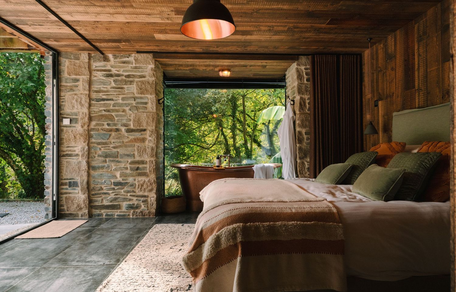 Modern rustic interior with wooden beams and stone walls features a cozy seating area bathed in natural light.