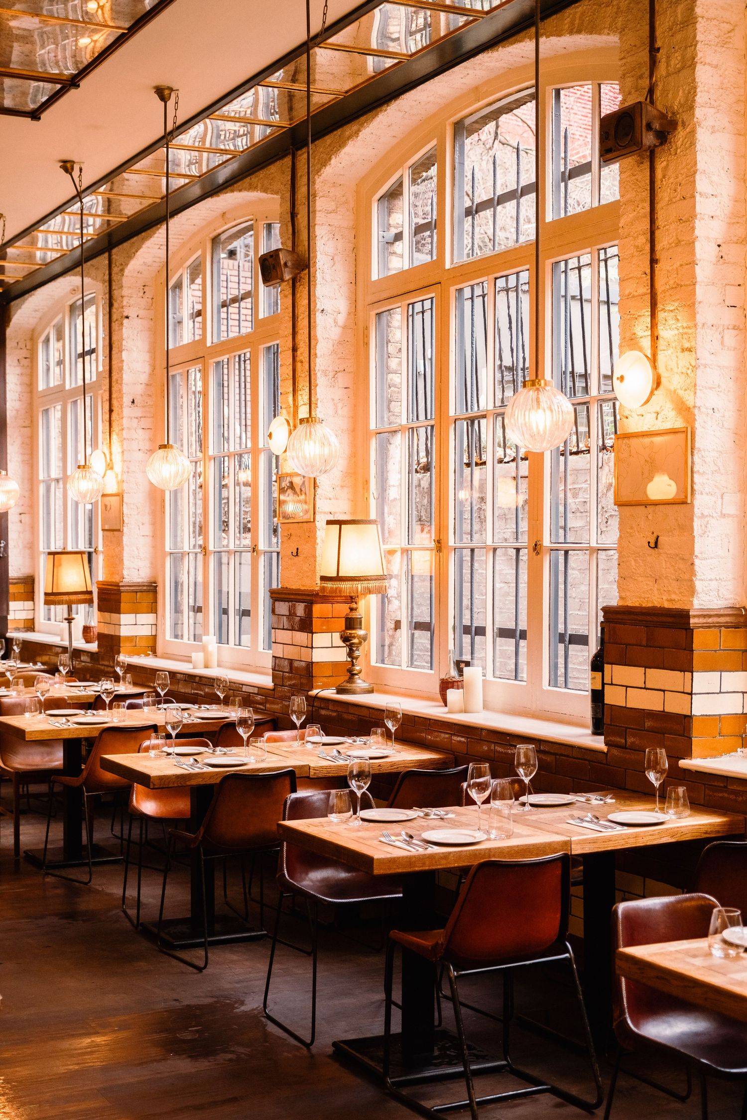 Industrial-chic restaurant interior with exposed brick walls, large windows, and pendant lighting.