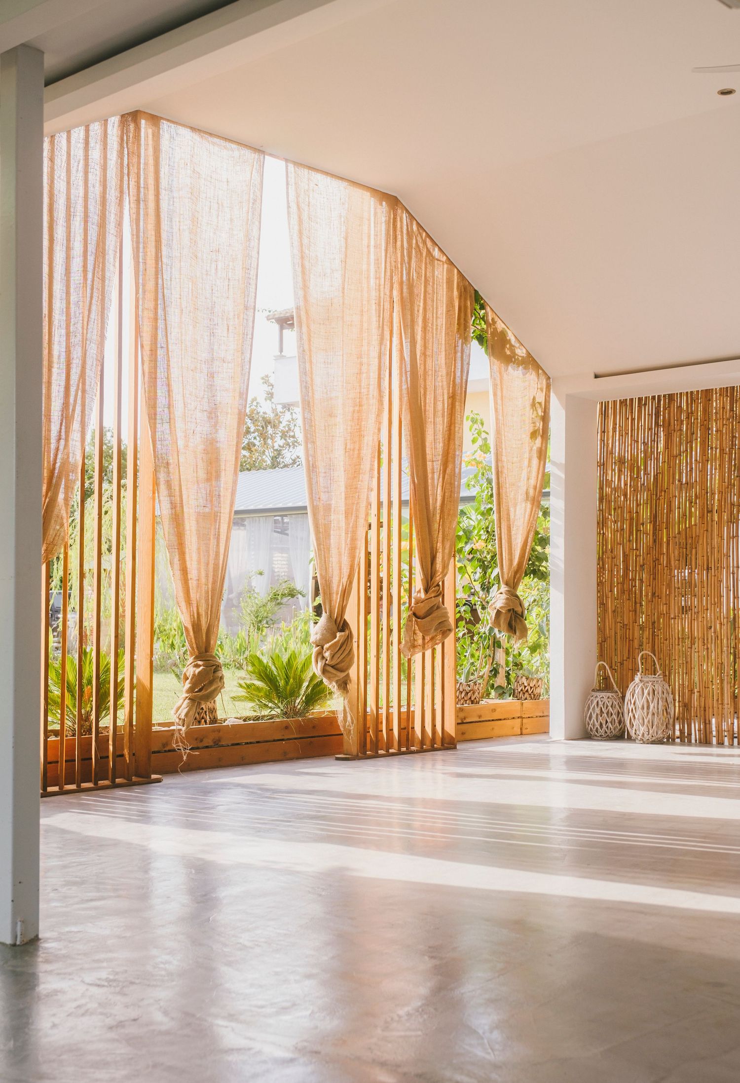 Minimalist yoga studio with bamboo curtains and white pillars bathed in natural light.