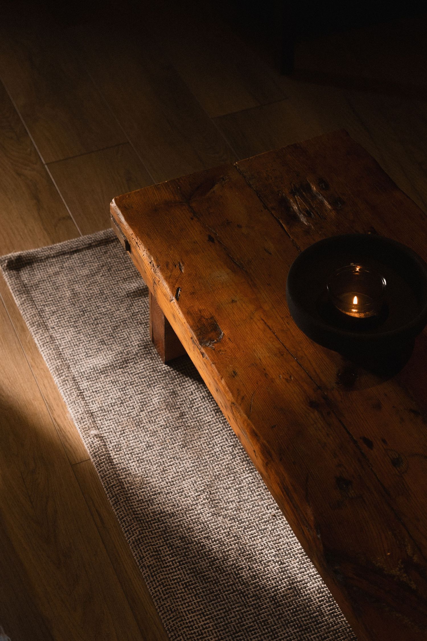 Dramatic lighting illuminates a dark wooden floor with a beam of sunlight creating a geometric pattern.