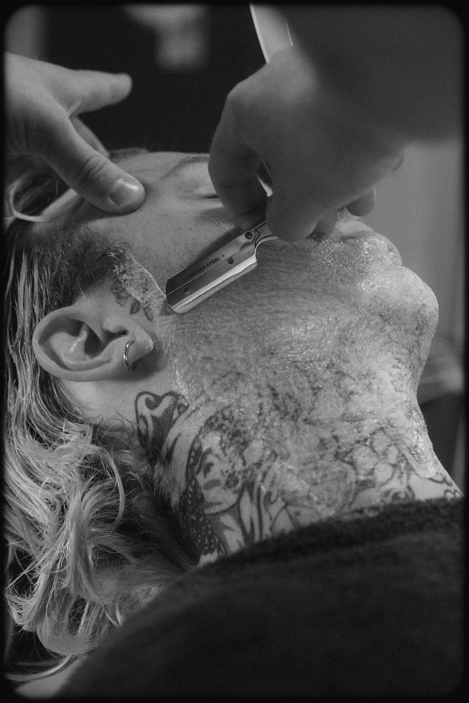 Black and white close-up sequence showing detailed tattoo work being done on skin with a tattoo machine.