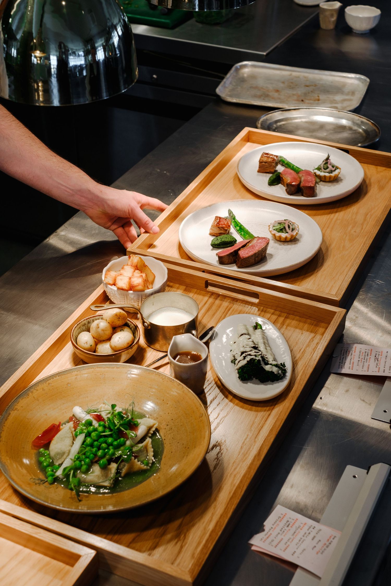 Elegant plated dishes on wooden serving boards in a fine dining setting.