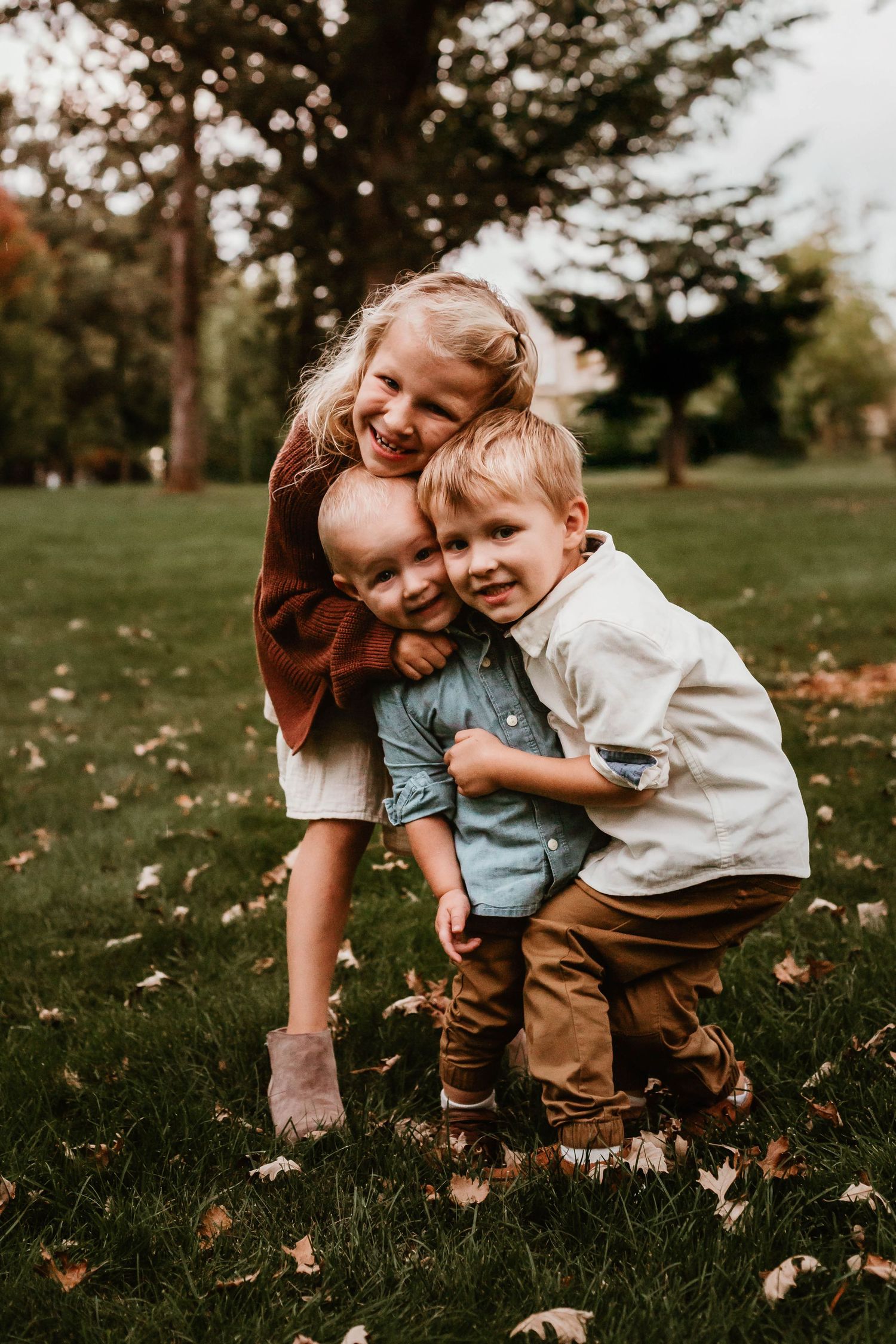 Three kids hugging in grassy field Southeast Minnesota