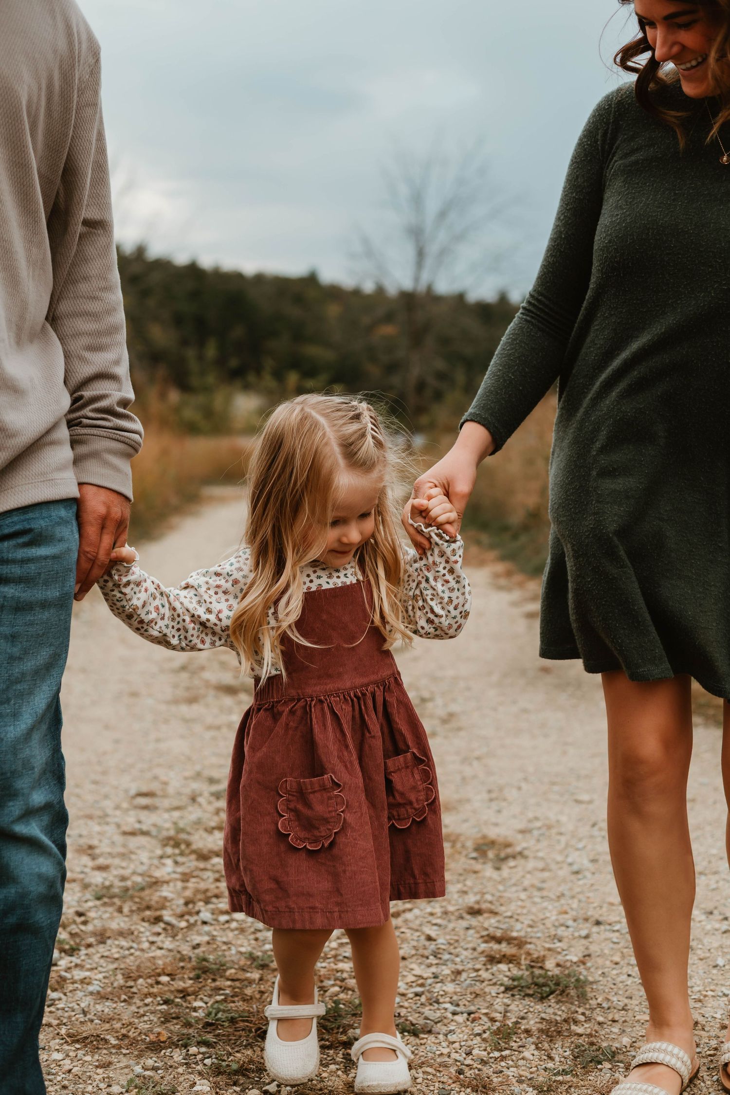 Family of three walking on gravel in grassy field Southeast Minnesota