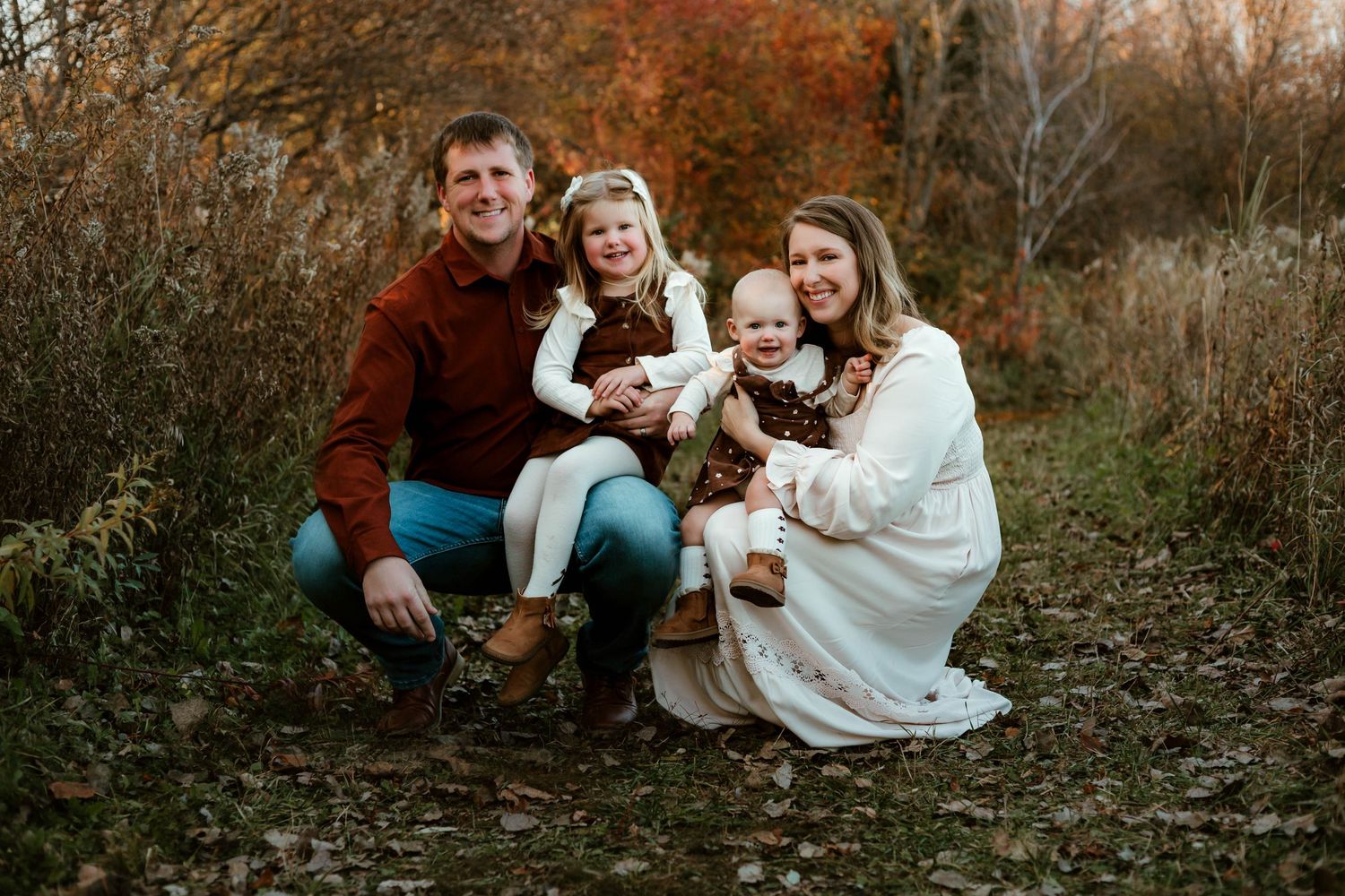 Family of four crouched down in grassy field Southeast Minnesota
