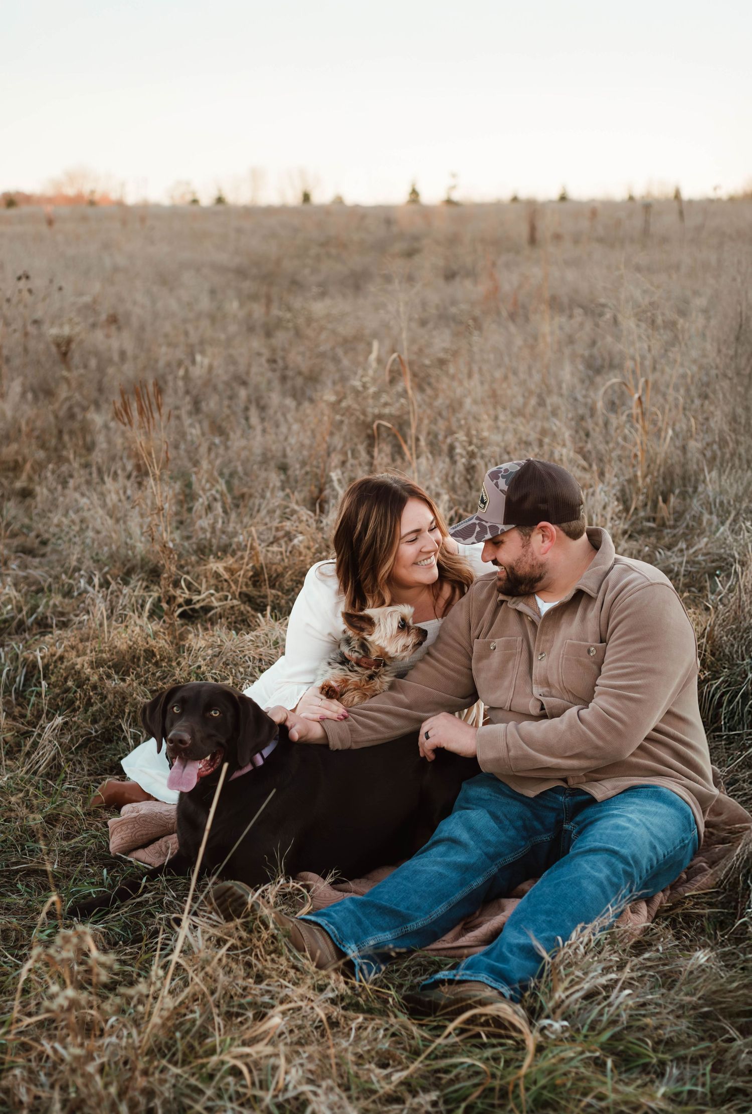 Couple cuddling dogs in grass field southeast minnesota