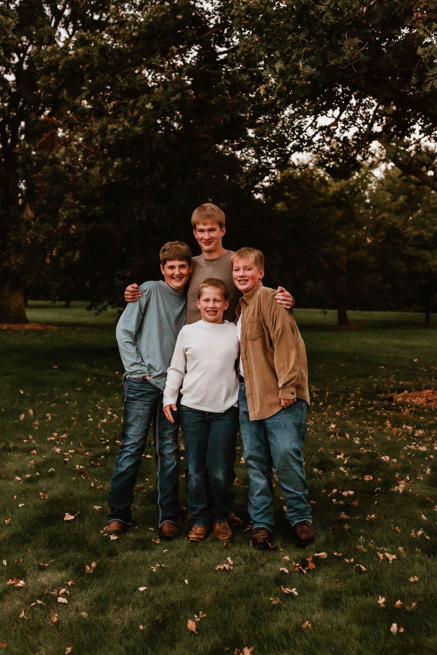 Four brothers hugging in grassy field Southeast Minnesota