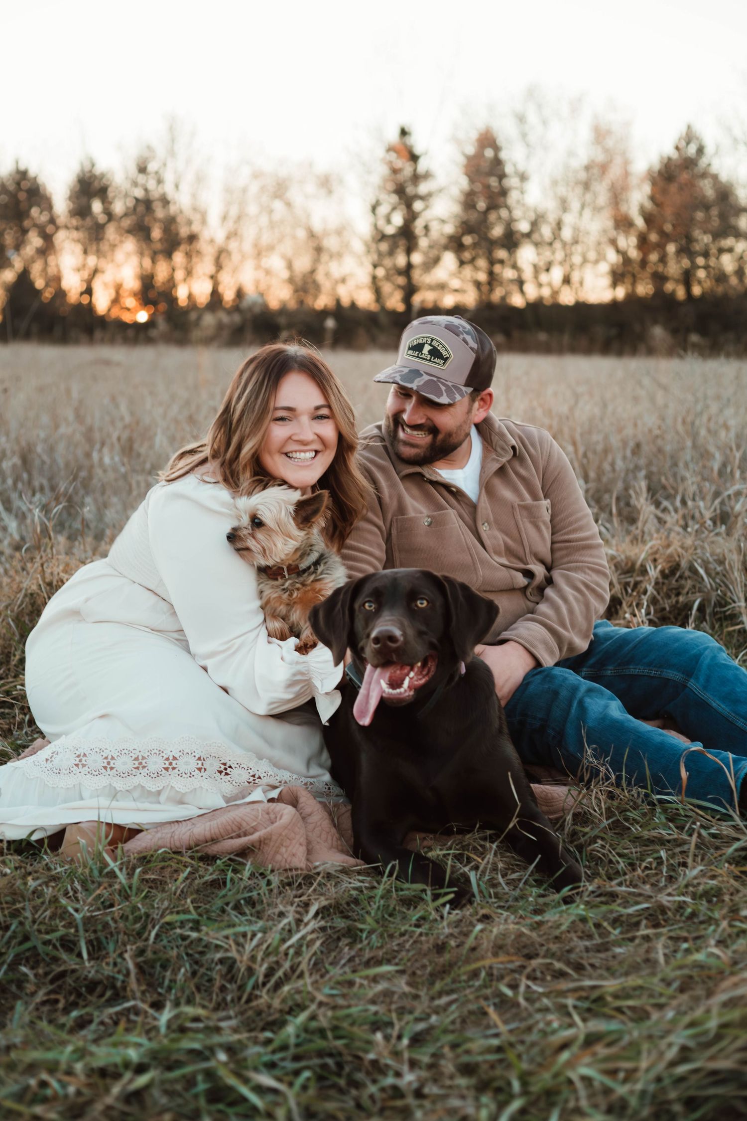 Couple cuddling with two dogs in field in Southeast Minnesota
