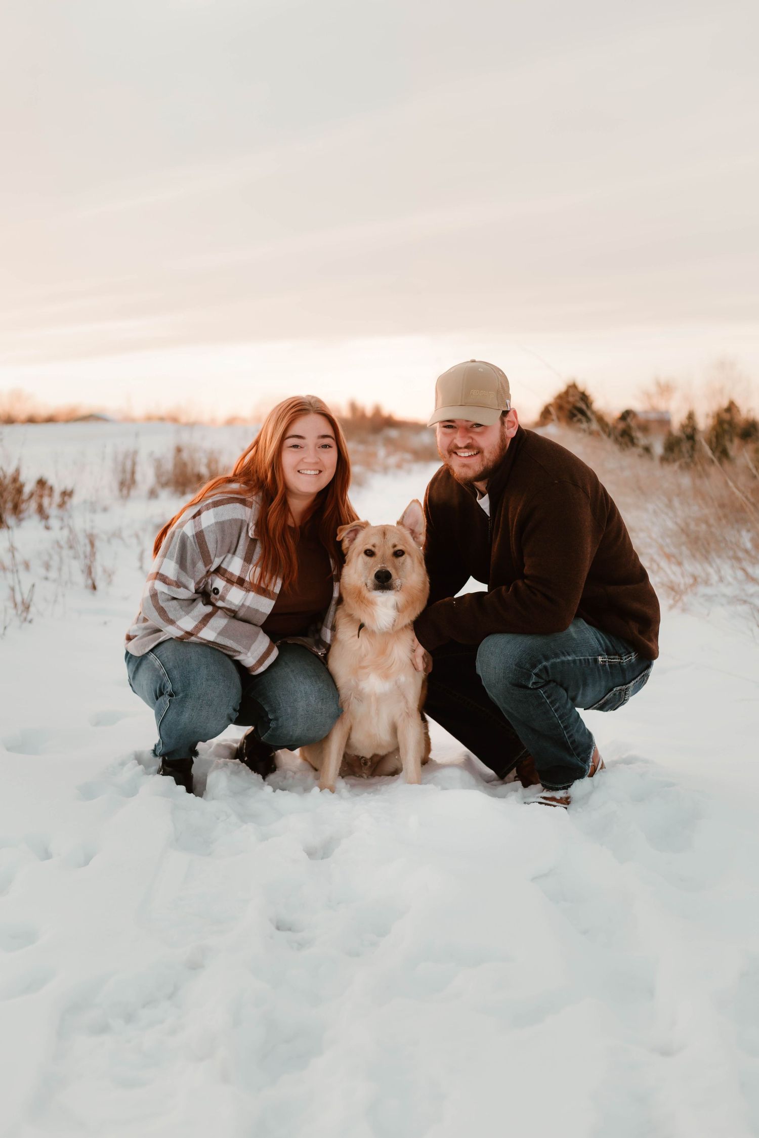 Couple and dog in snowy field Southeast Minnesota