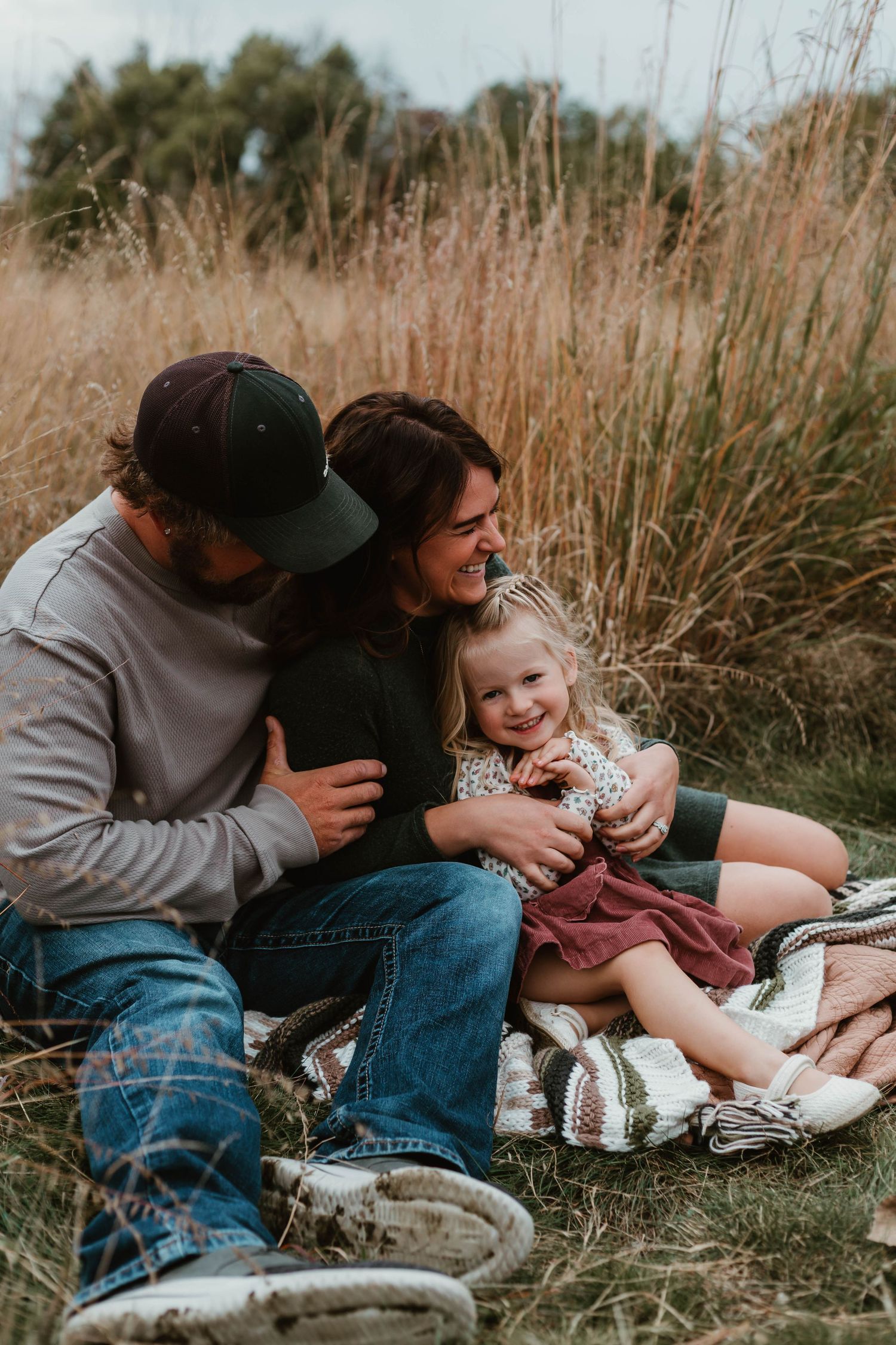 Family of 3 cuddling in tall grass in Southeast Minnesota