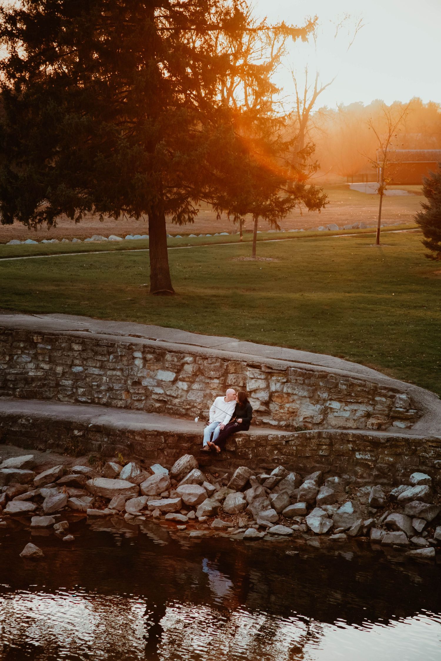Couple kissing while fishing off retaining wall in Southeast Minnesota