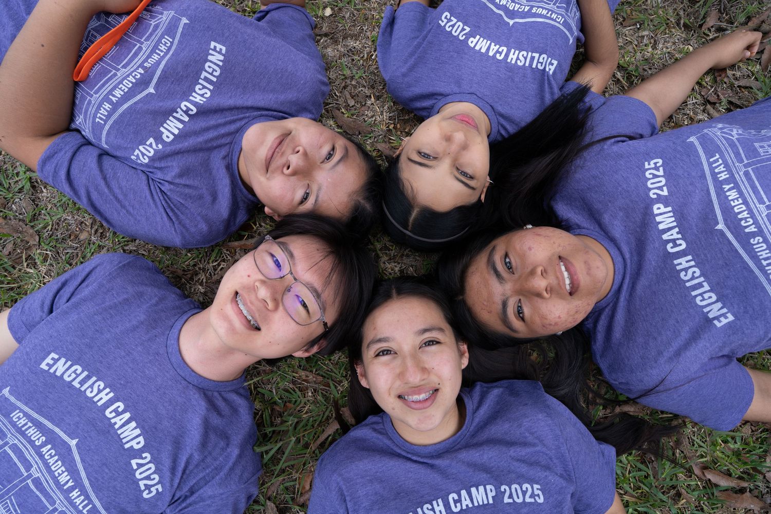 Outdoor group portrait of students lying in a circle during a school event