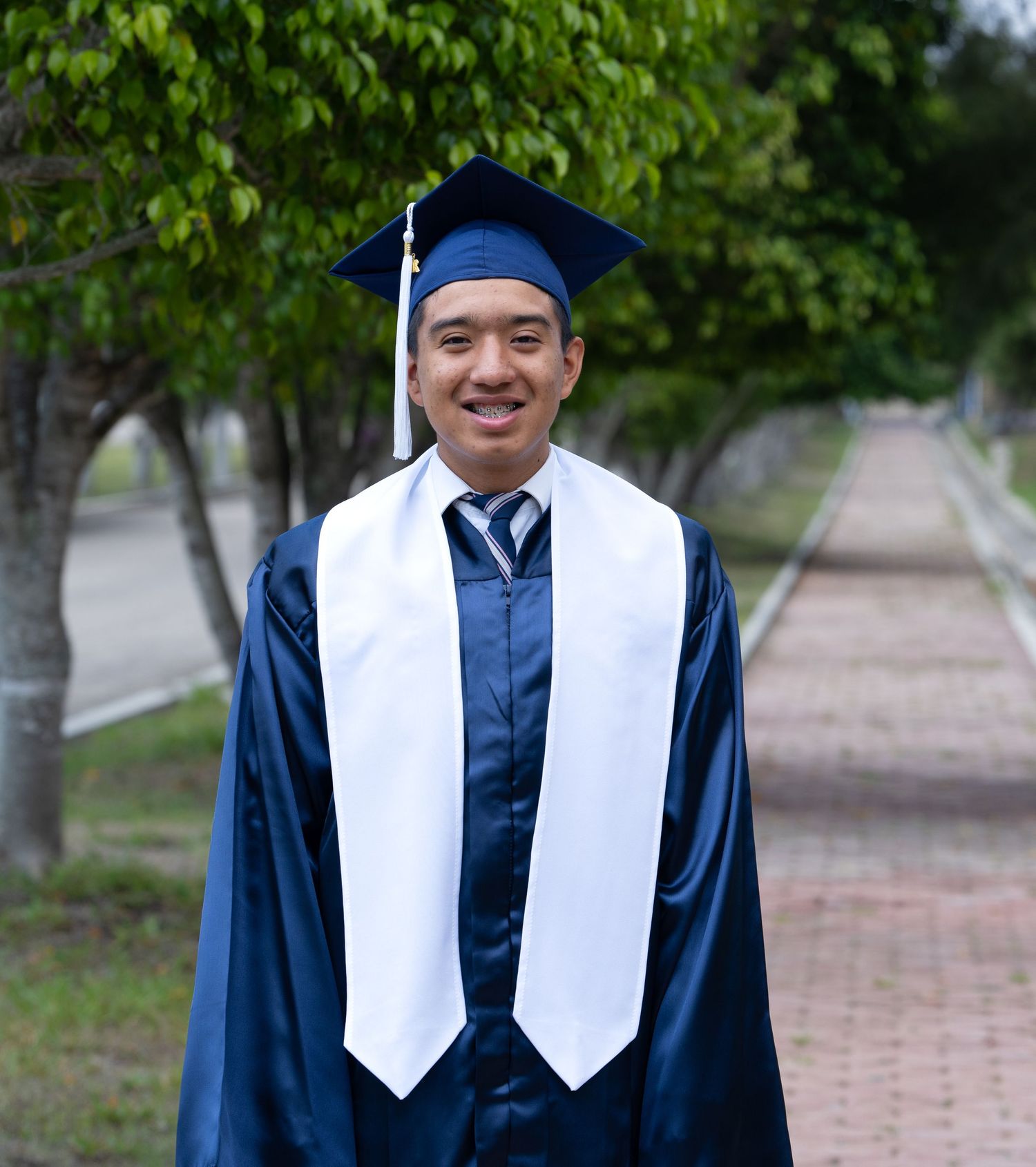 Graduate wearing a cap and gown, smiling during an outdoor graduation portrait session.