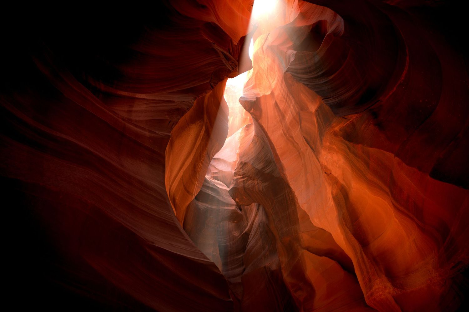 Sunbeams illuminate the red-orange sandstone walls of Antelope Canyon in Arizona.