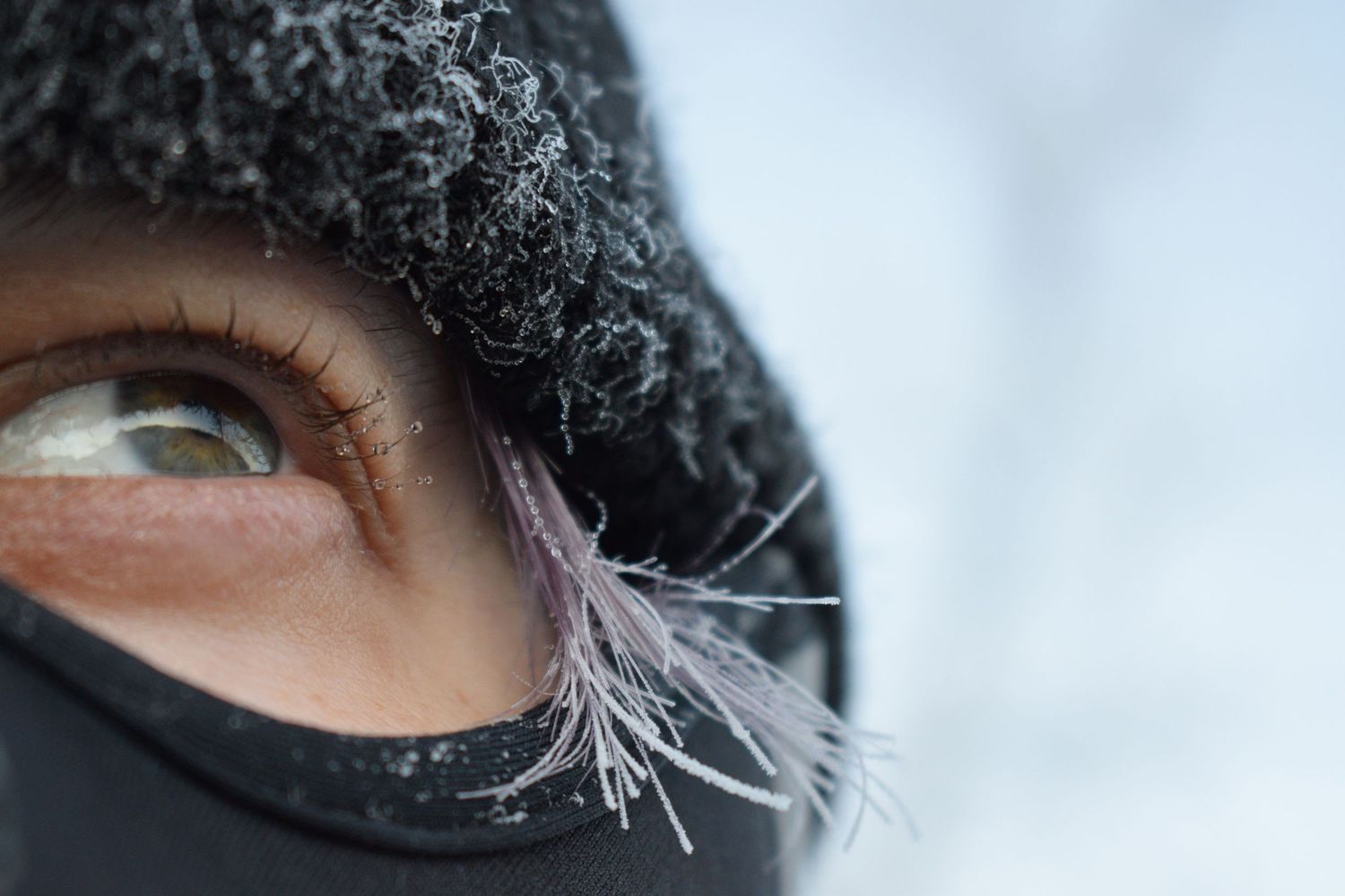 Close-up portrait of Alexander Mann in subzero conditions in Abisko, Sweden, with frozen ice crystals forming on a face mask and hair.
